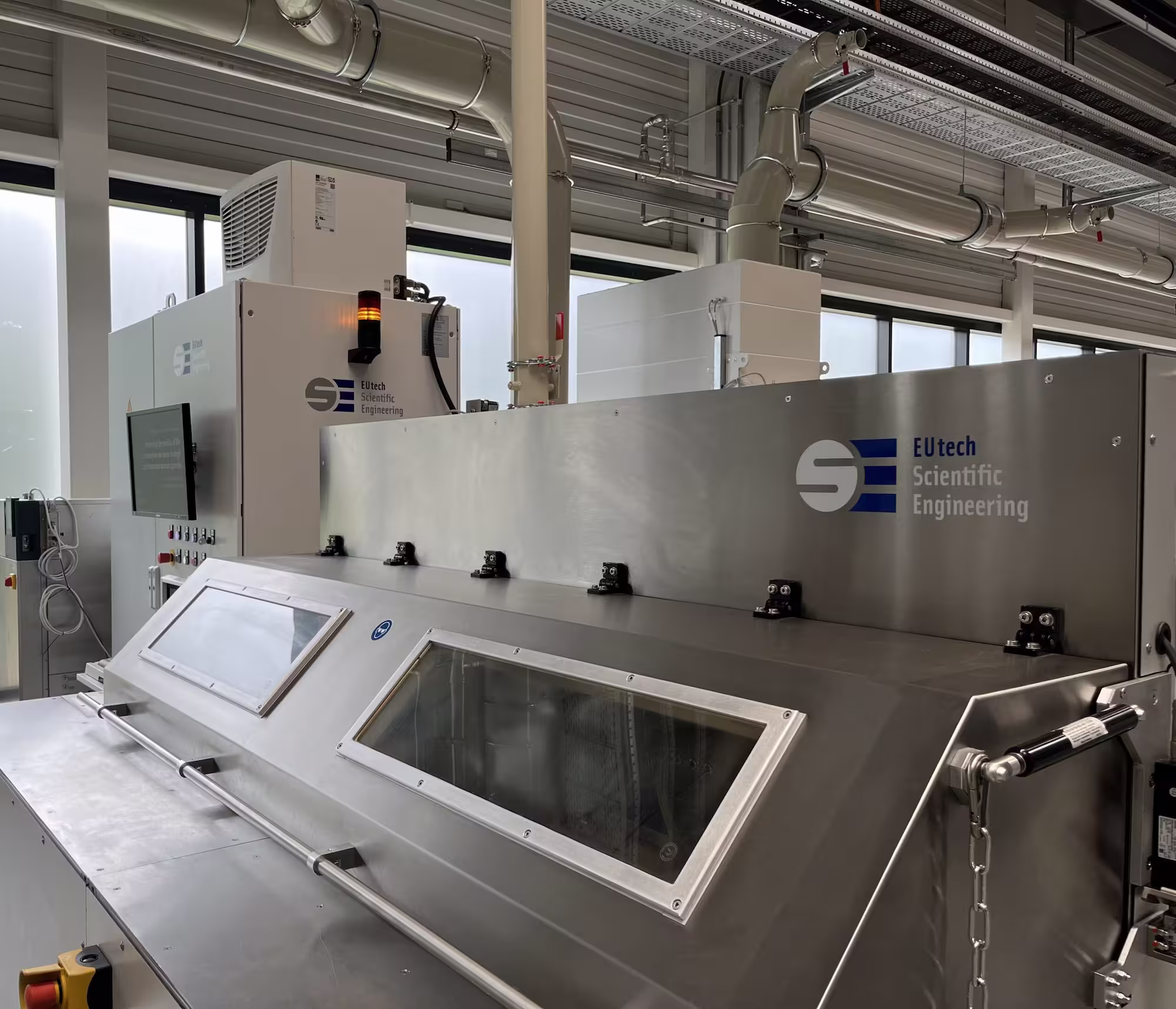 Large industrial EUtech Scientific Engineering testbench with viewing windows in a factory setting.