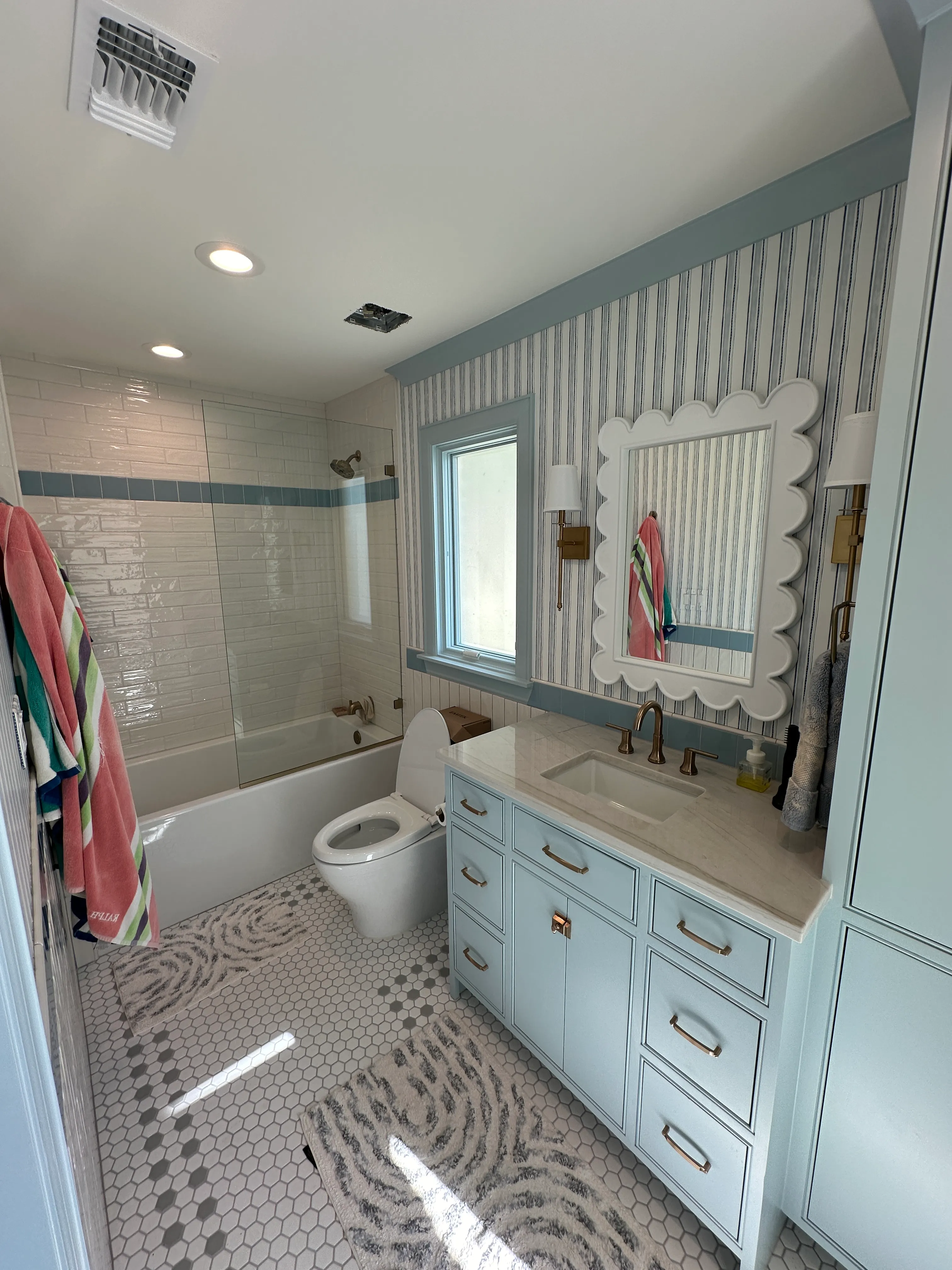 Kids bath with scalloped mirror and striped wall tile