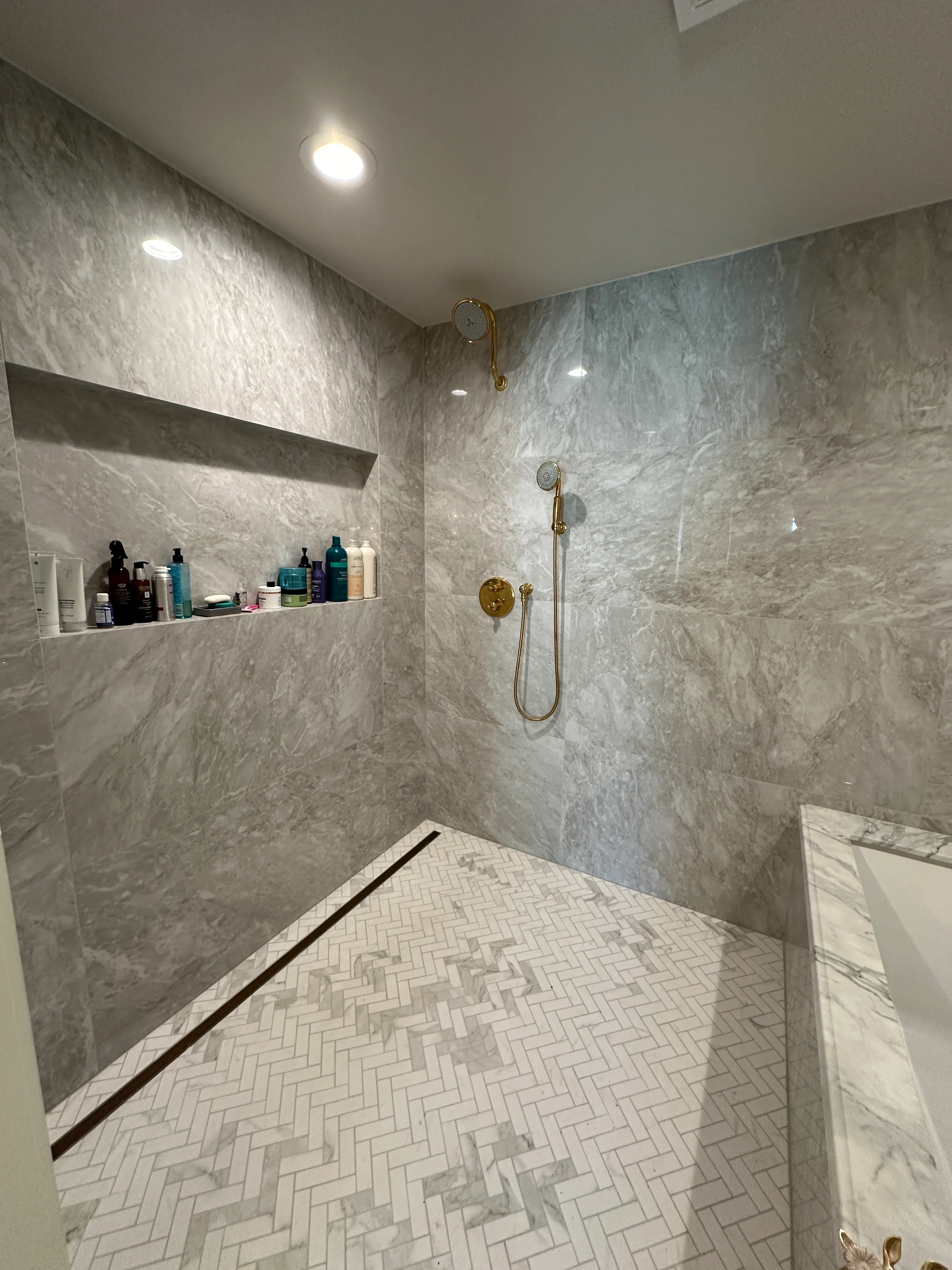 Marble-clad walk-in shower with brushed brass fixtures