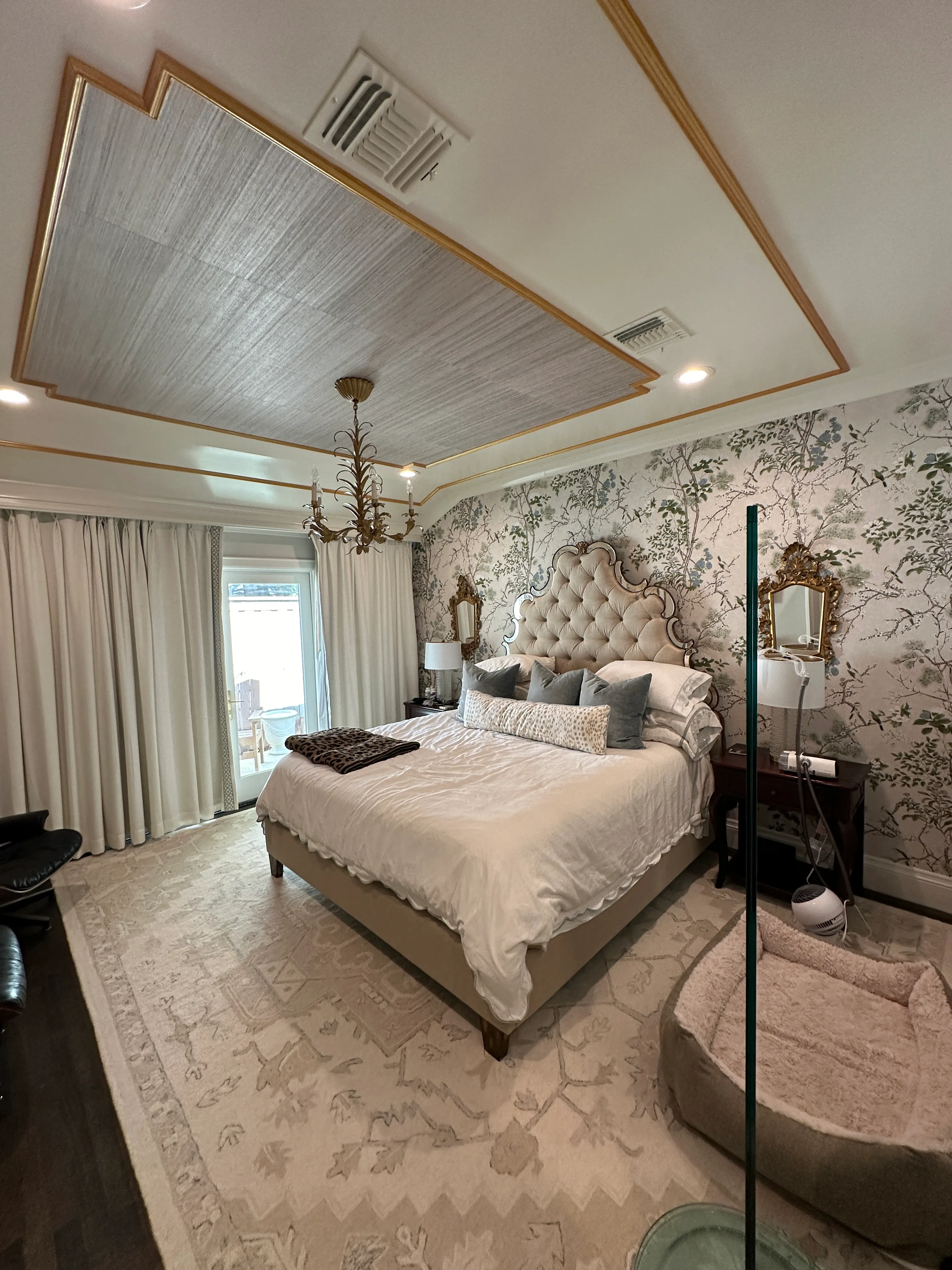 Bedroom with tufted headboard and wallpapered feature wall