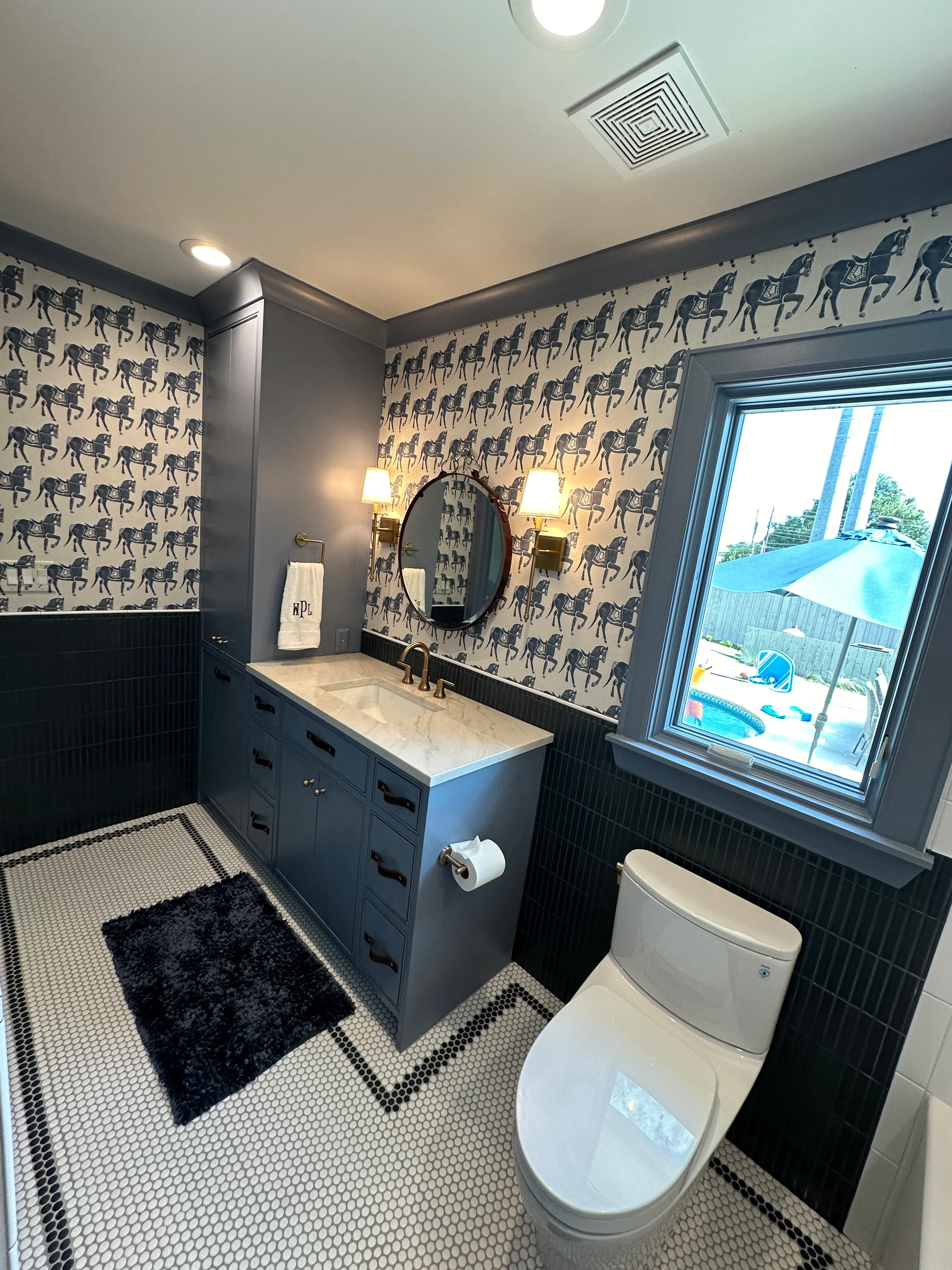 Powder bath with navy cabinetry and round mirror
