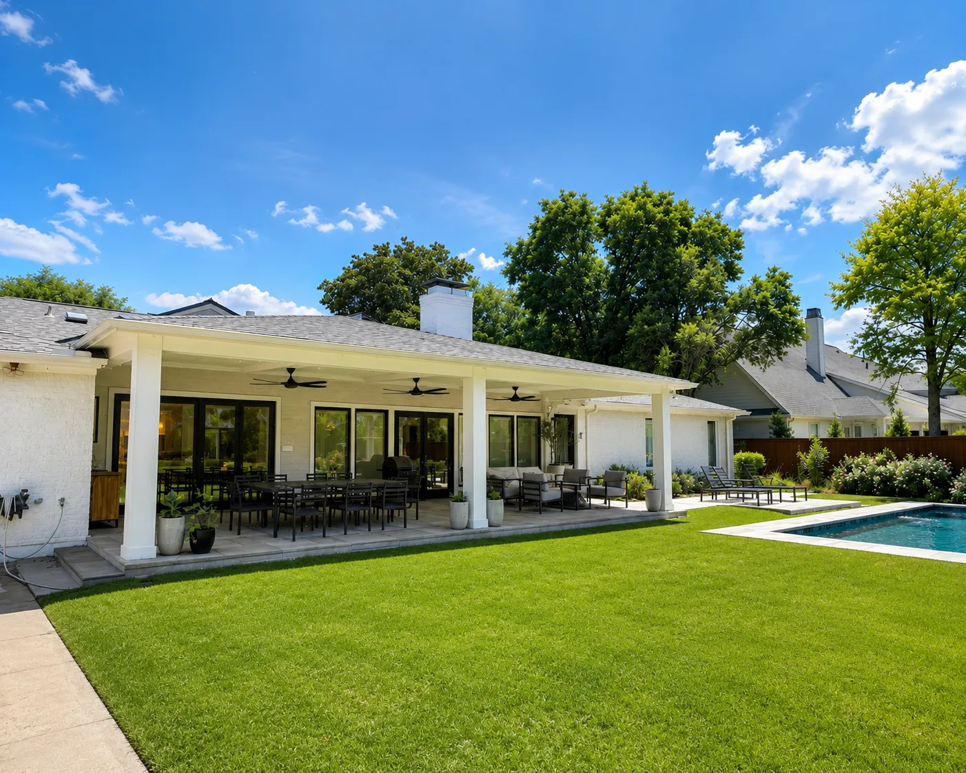 Covered rear patio with ceiling fans overlooking lawn and pool