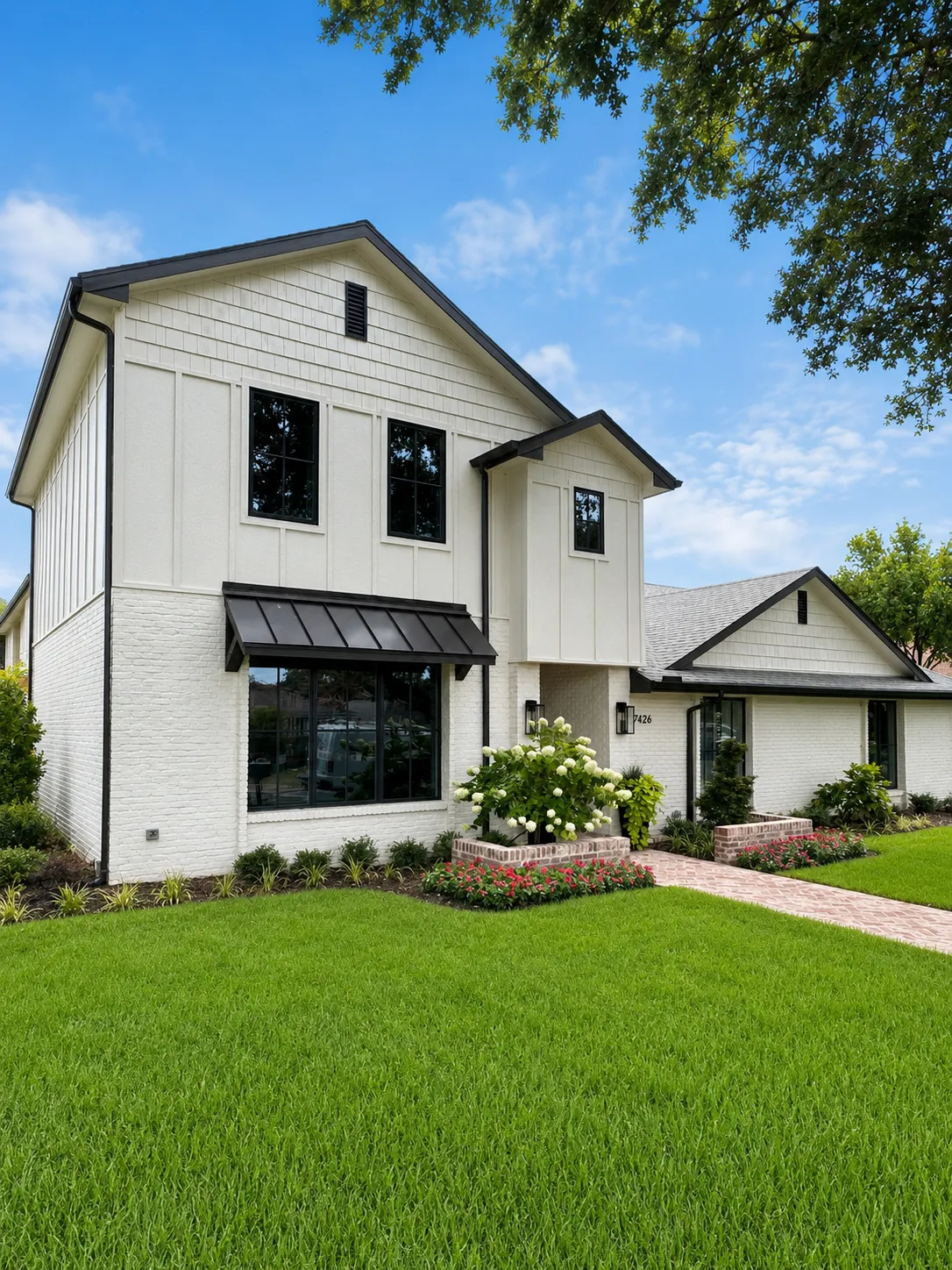 Finished two-story white board-and-batten home with black windows and metal awning
