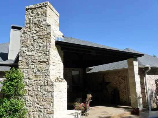 Stone chimney and covered patio with brick exterior