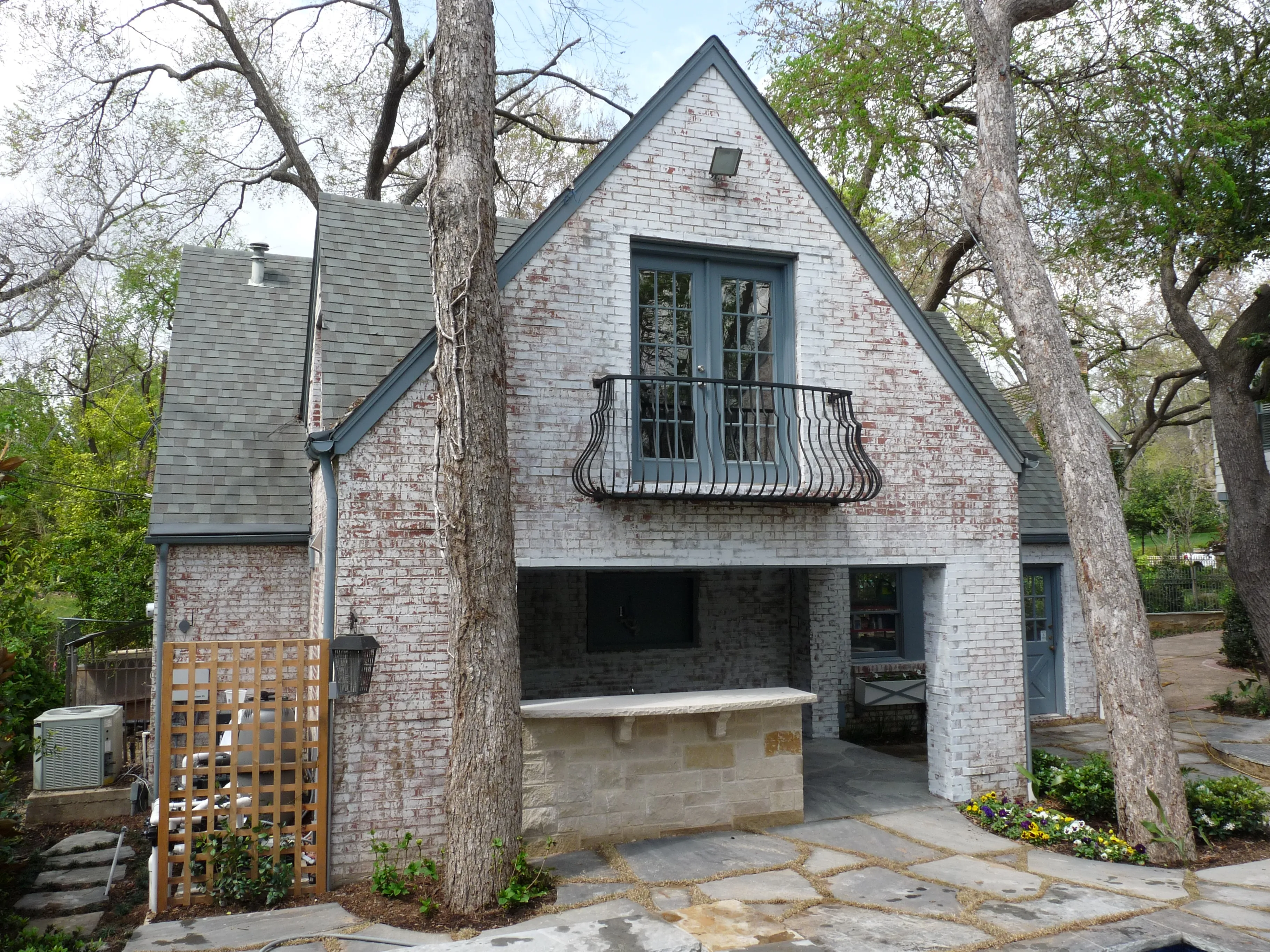 Whitewashed brick cottage with Juliet balcony and outdoor kitchen below