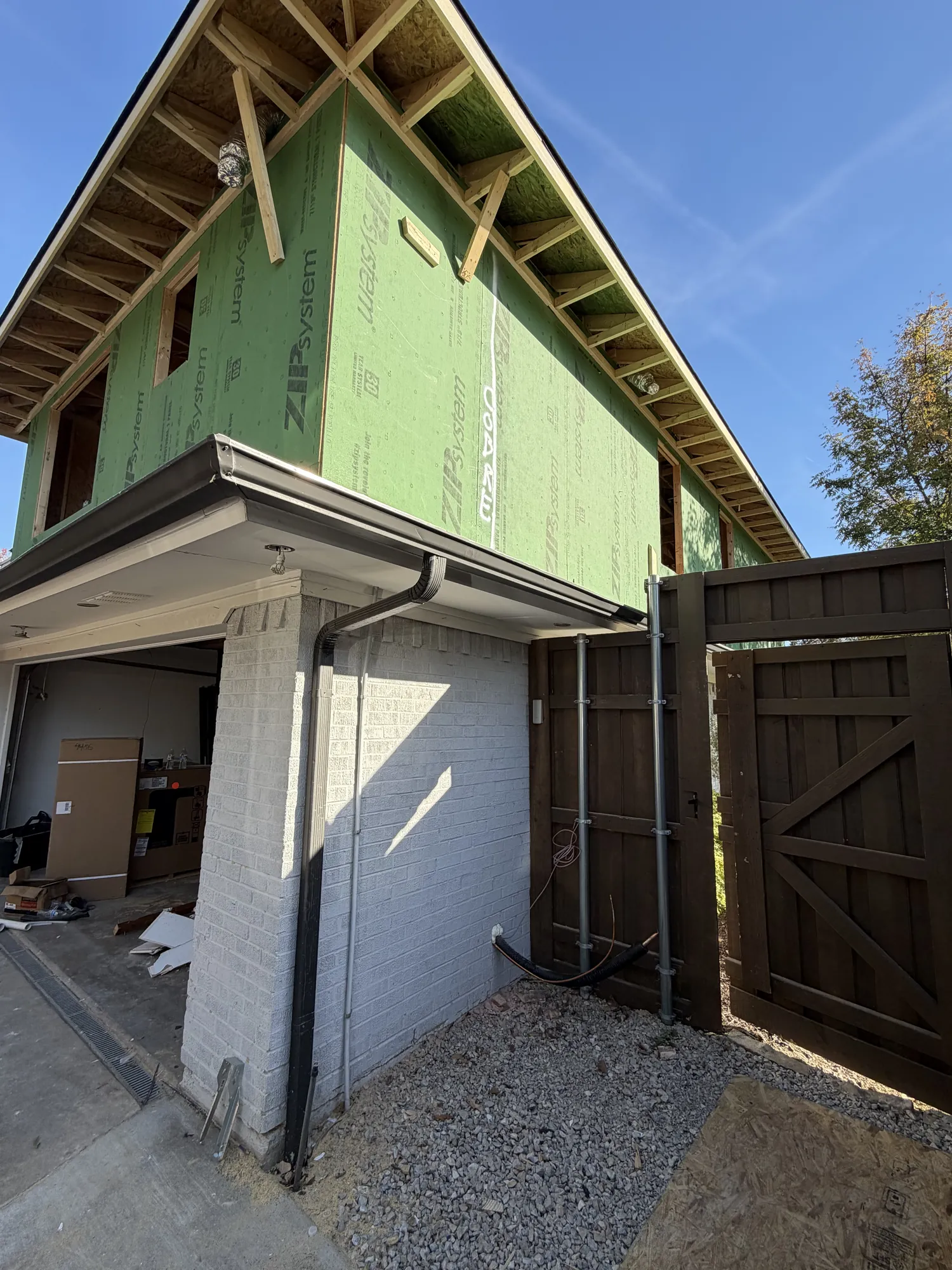 Side of the home showing the new second-story wall in ZIP System sheathing above the existing brick wall