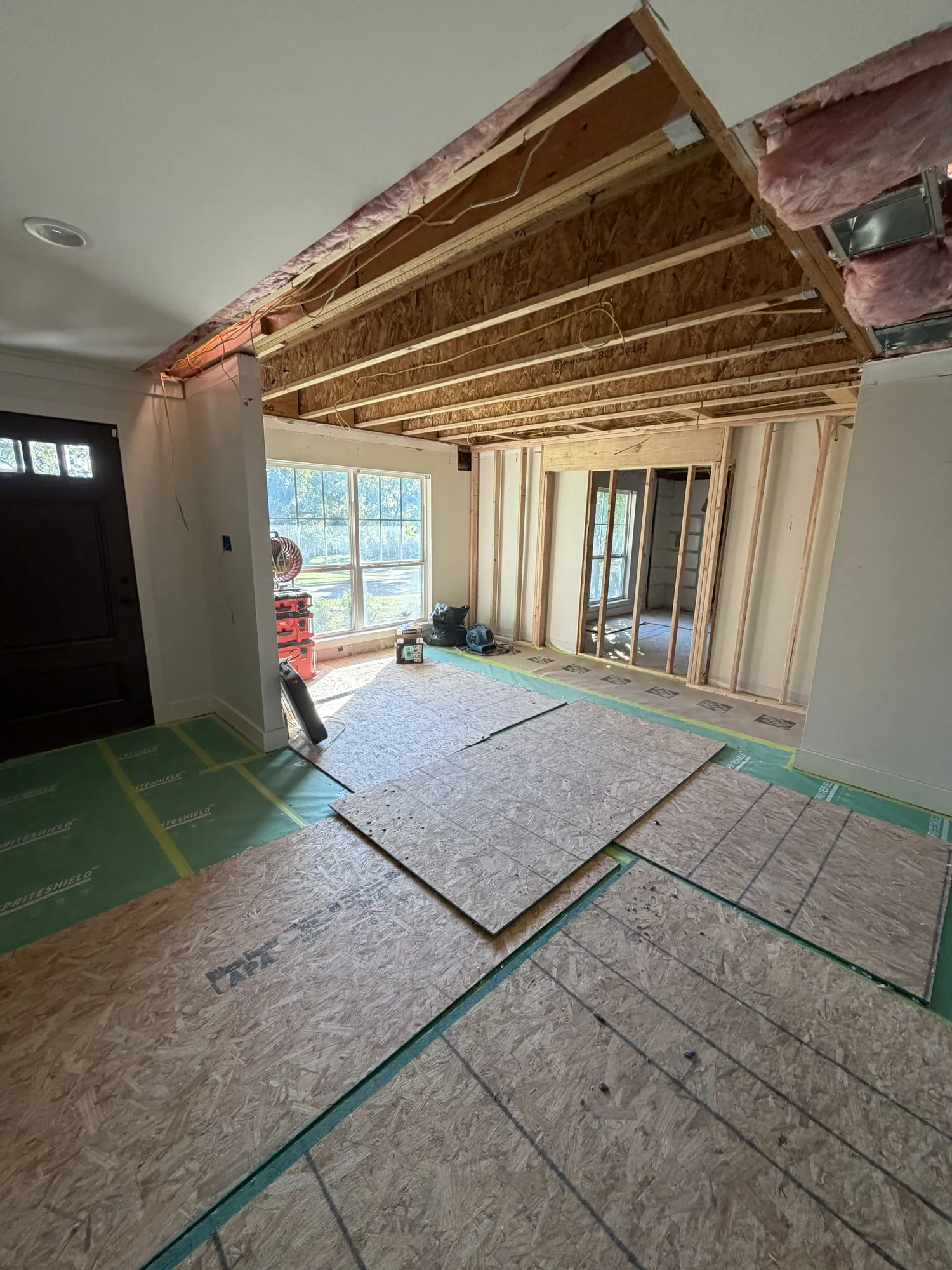 First-floor living area with the ceiling opened up to the new second-floor joists, floors protected