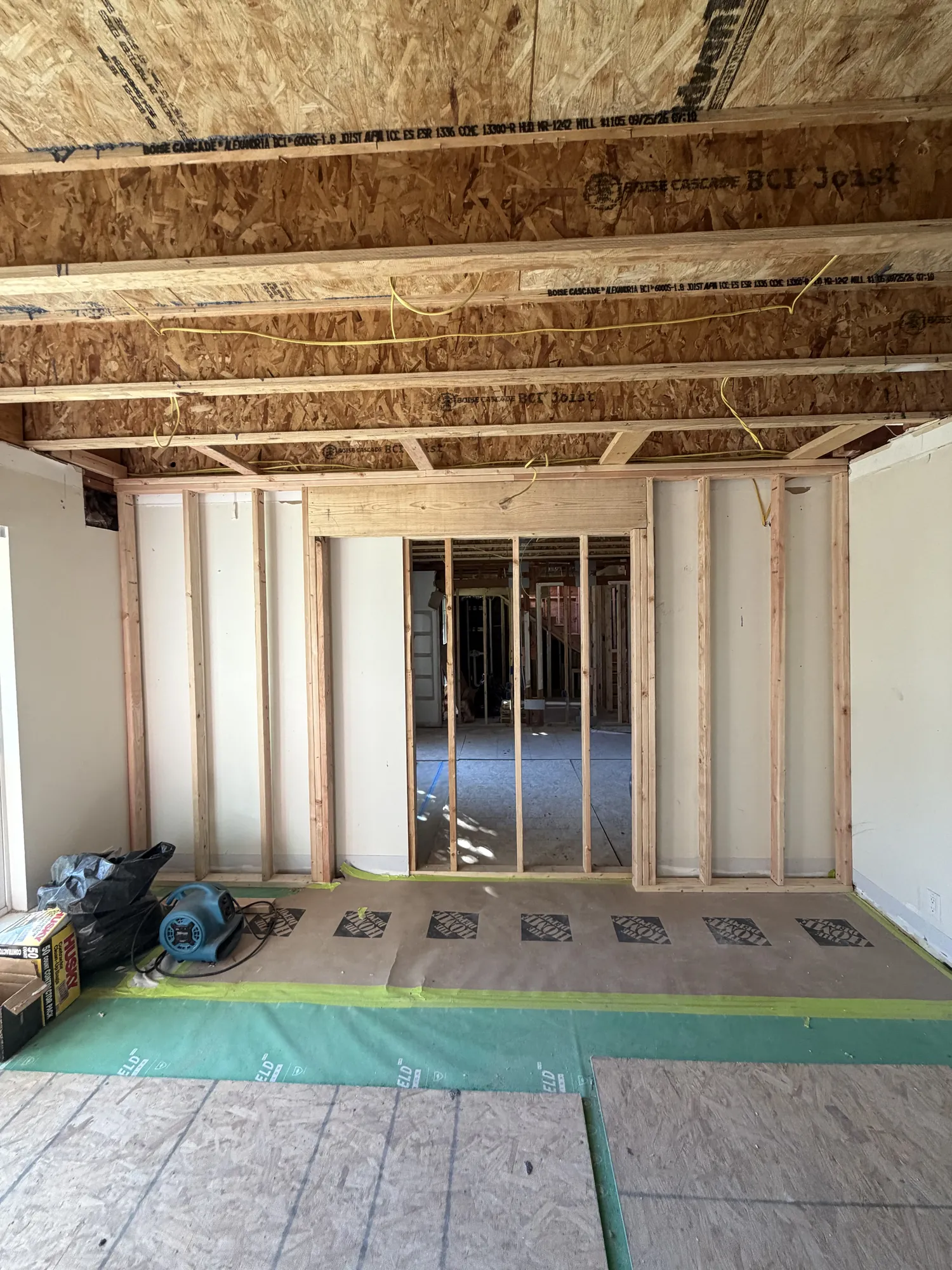 Wall opening framed beneath new engineered BCI floor joists, with protective paper on the floor