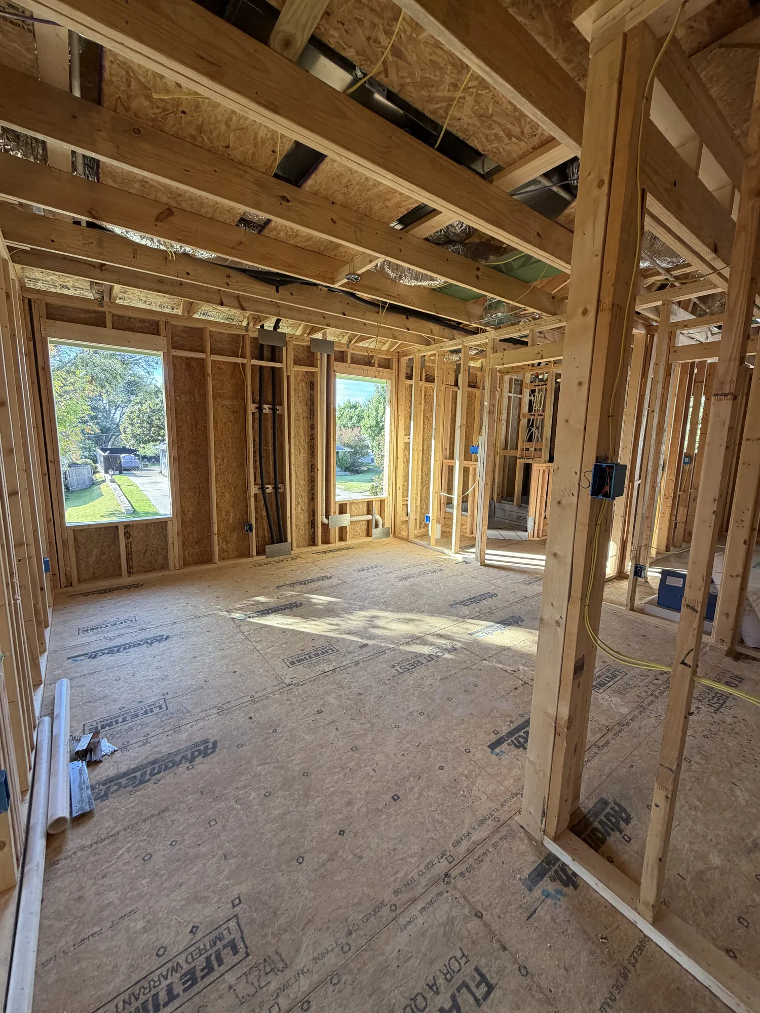Second-floor room with framed window openings, subfloor and ductwork overhead