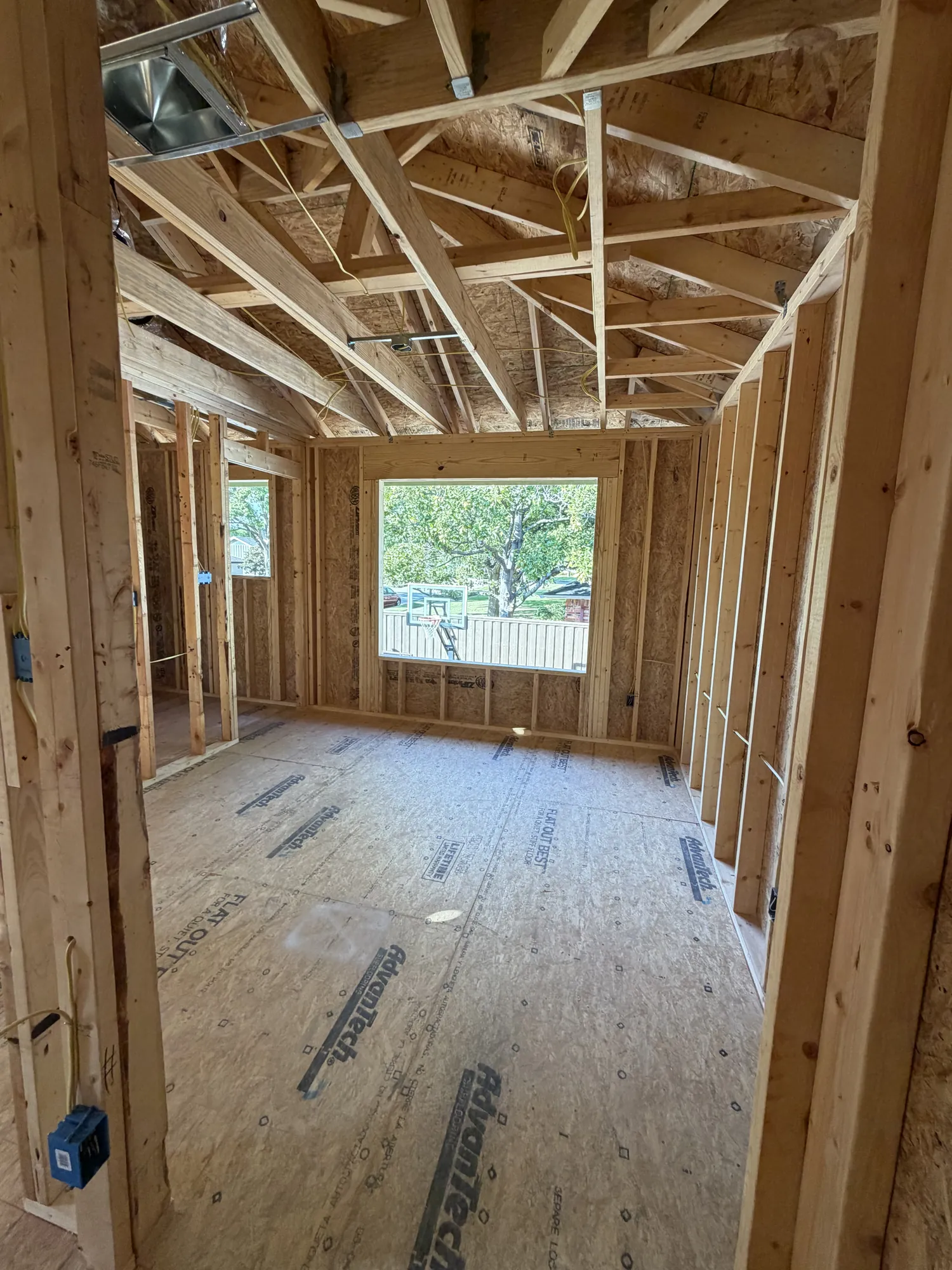 Second-floor room framed with a large window opening and roof trusses overhead