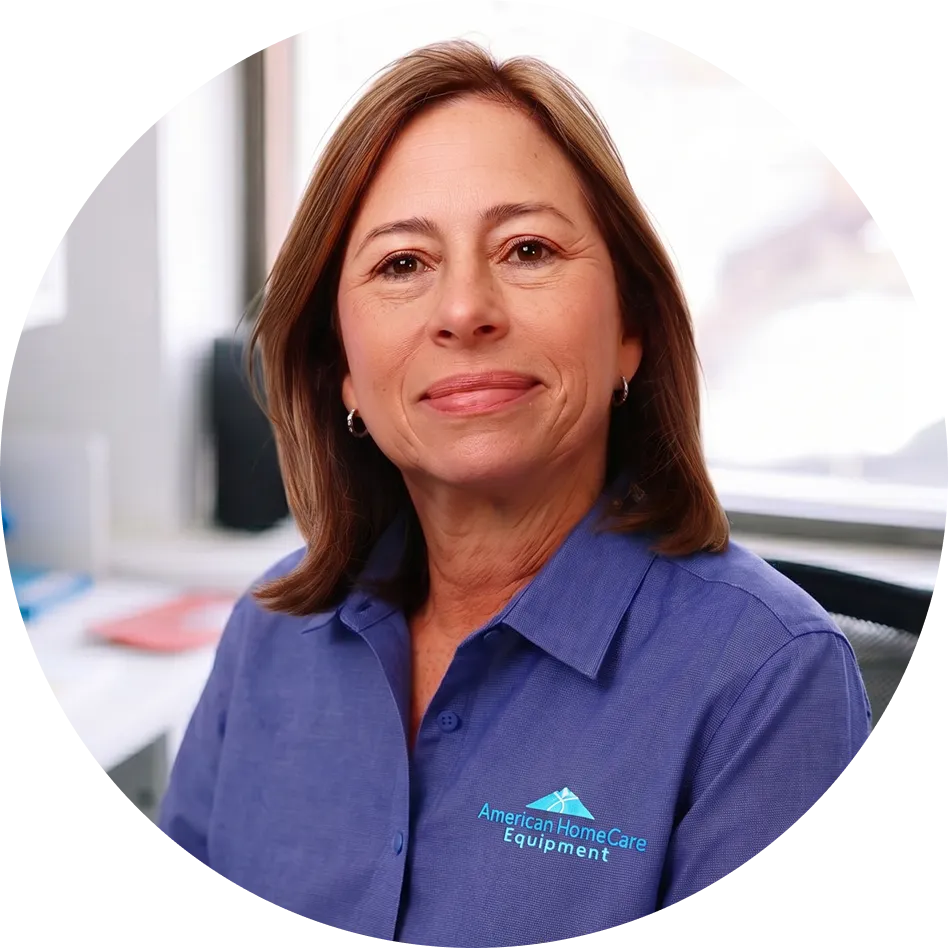 Smiling woman in a blue American HomeCare Equipment shirt in a bright office setting.