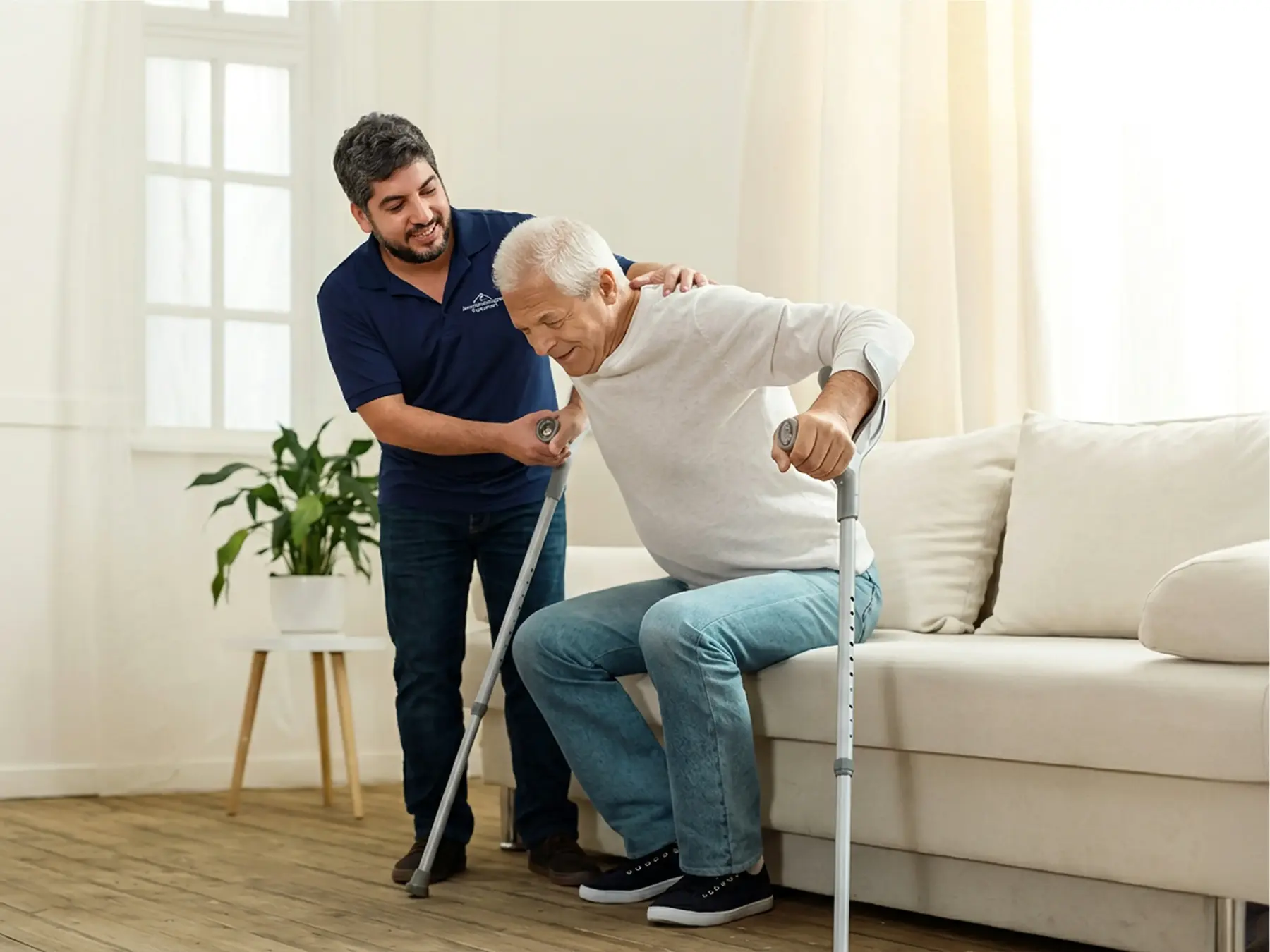Man with crutches receiving assistance to stand up from a caregiver in a bright living room.