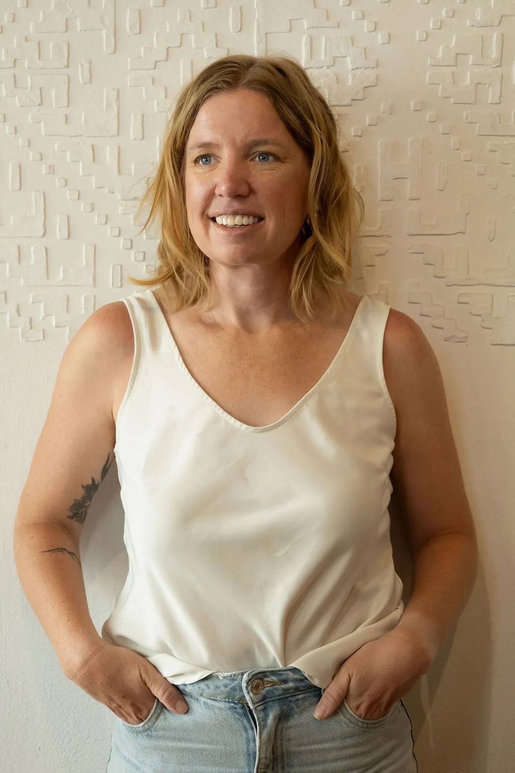 Rebecca Nash, fractional Director of Operations, smiling against a white textured wall.