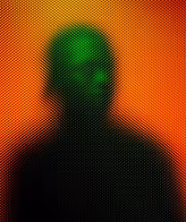 Silhouetted person with a green-lit face against an orange background, viewed through a textured surface creating a dotted pattern.