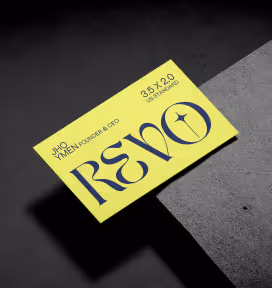 Yellow rectangular card with stylized text reading 'REVO' and smaller text above it, casting shadow on a dark textured surface.