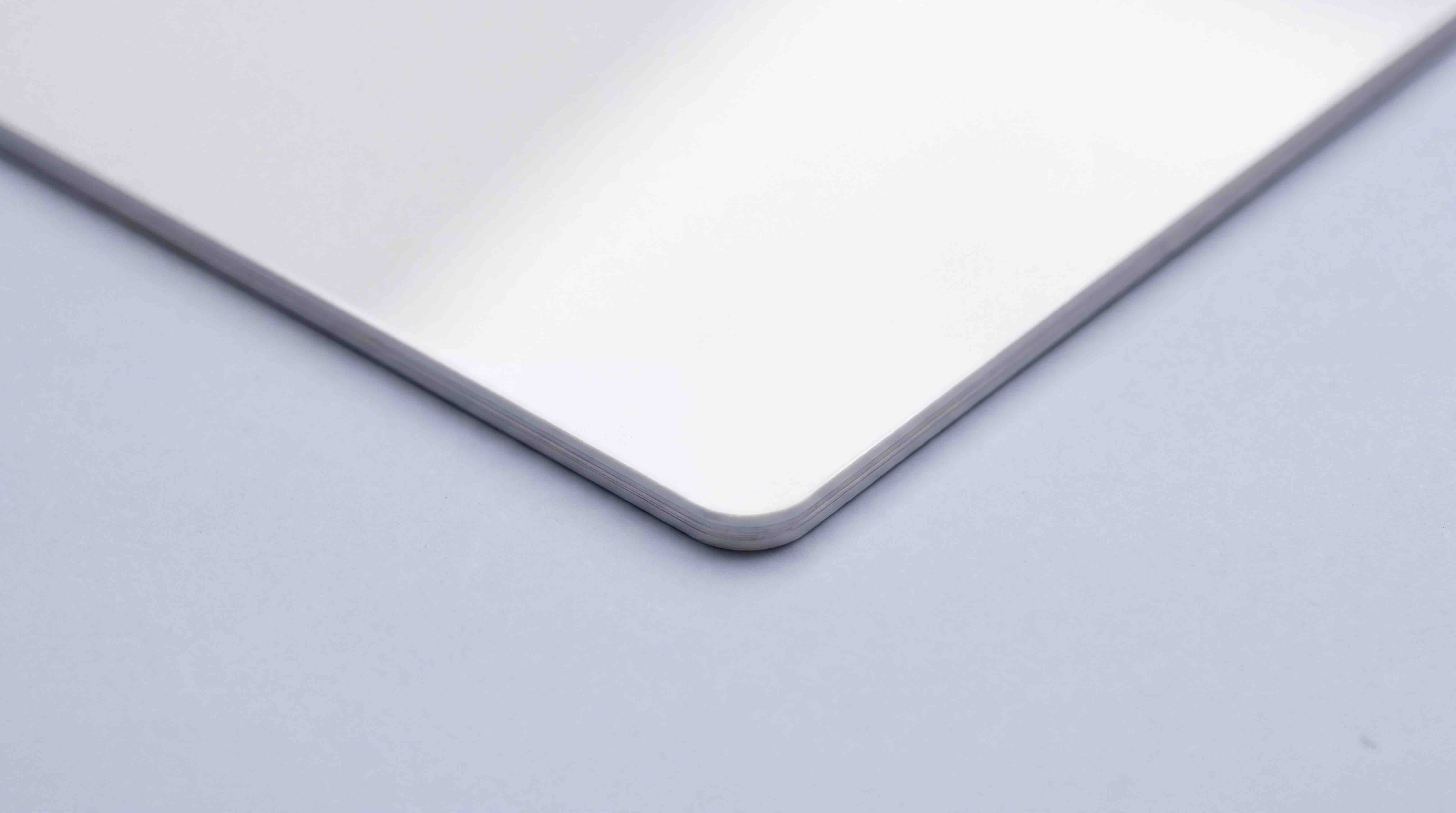 Close up of the corner of a gloss white PVC card, showing the laminated edge