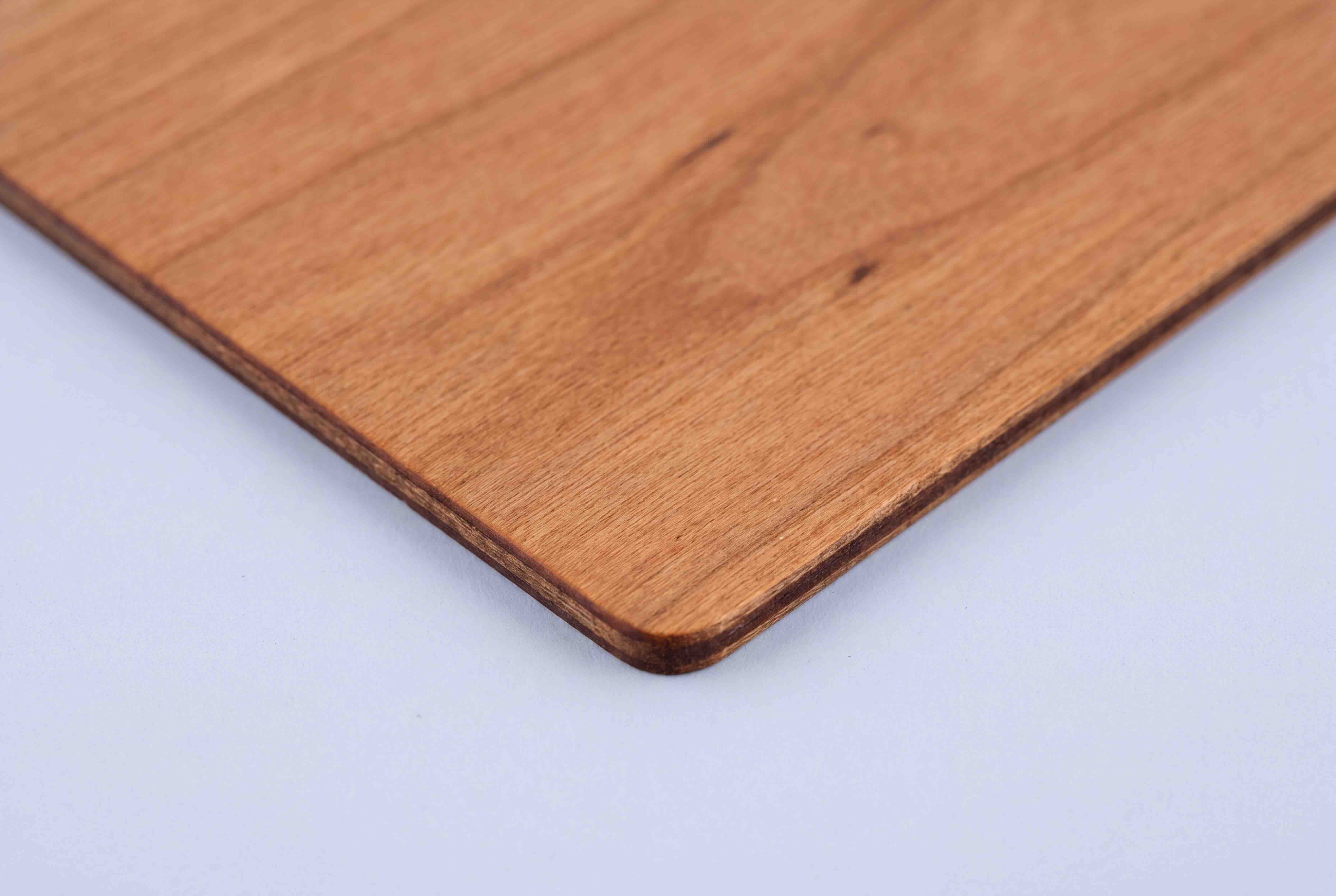 Close up of the corner of a cherry wood card, showing the grain and the laser cut edge