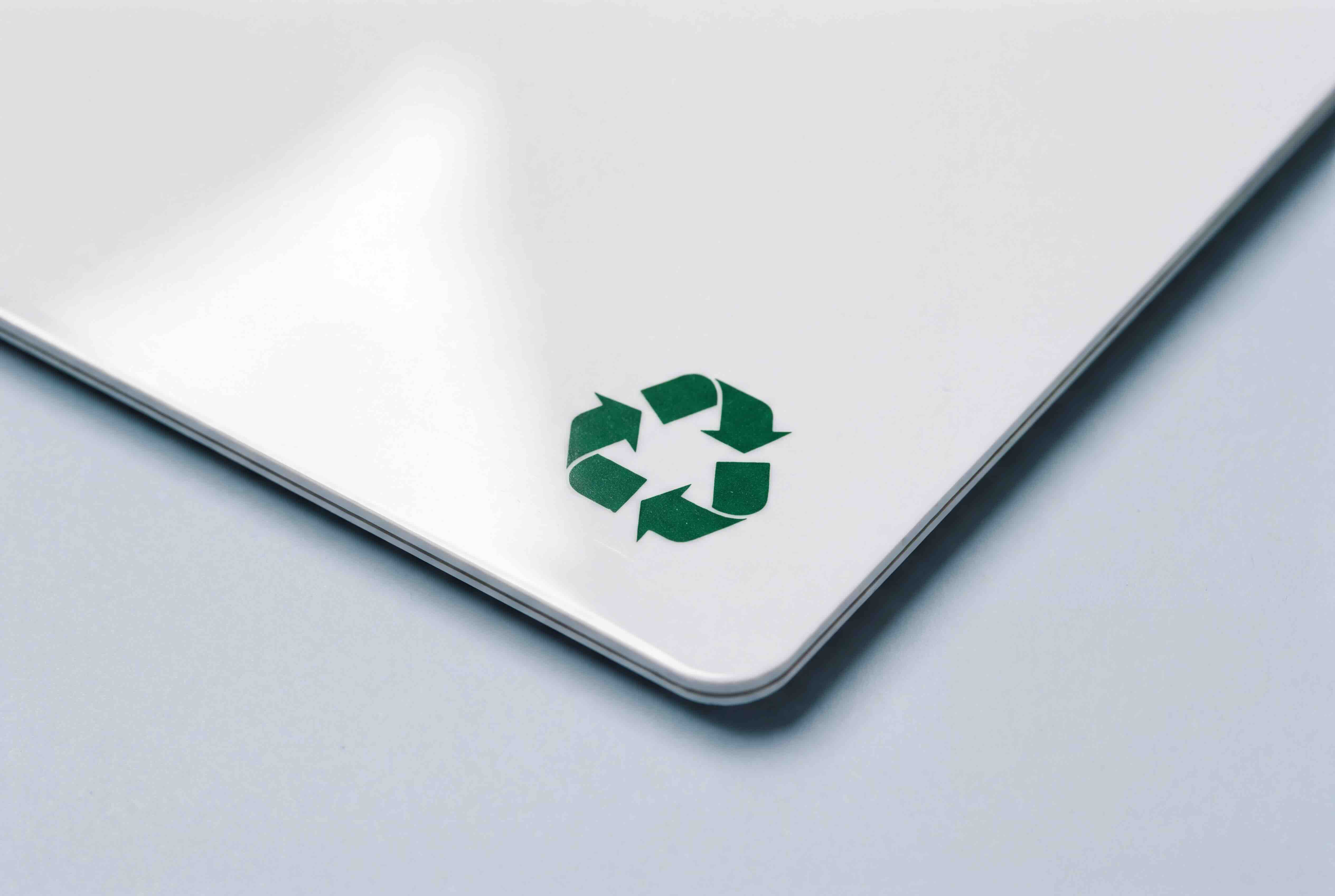 Close up of the corner of a recycled PVC card, printed with a green recycling symbol