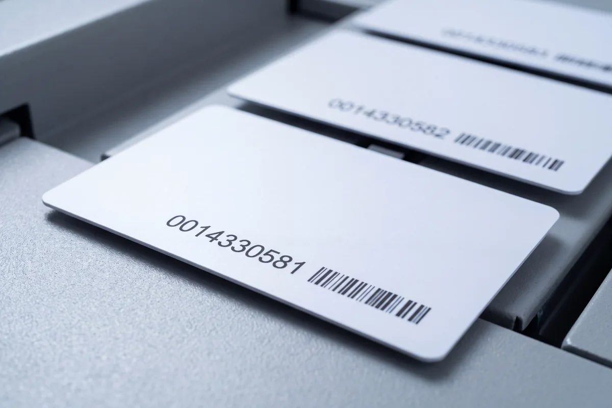 Cards leaving the personalisation line, each printed with its own sequential number and barcode.