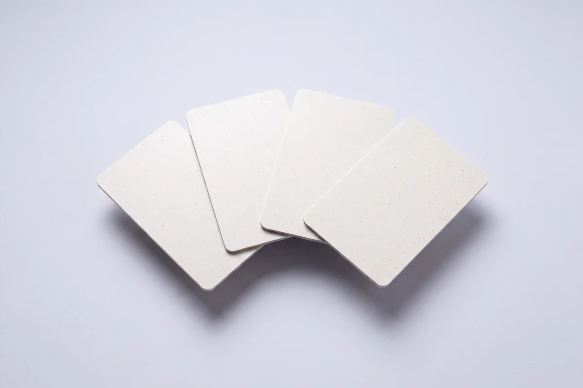 Four blank cards fanned out, made from a recycled PVC core, the reclaimed material visible as a fine speckle.