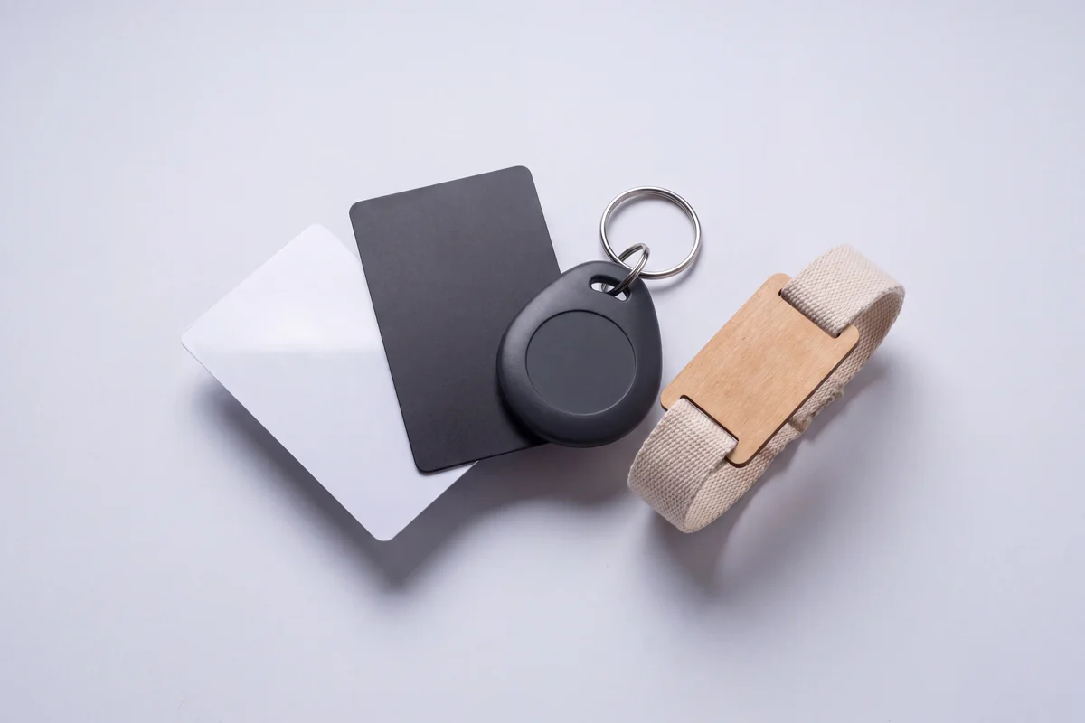 Four blank card bodies fanned out in gloss white PVC, matte black PVC, frosted translucent PVC and clear PET.