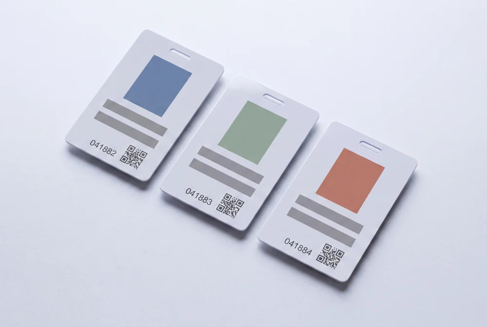 Three vertical badge cards with photo areas, printed data lines and QR codes
