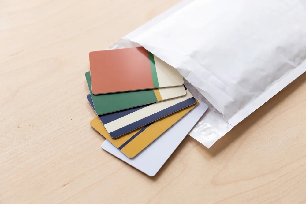 A single access card sliding out of a plain unprinted white mailer