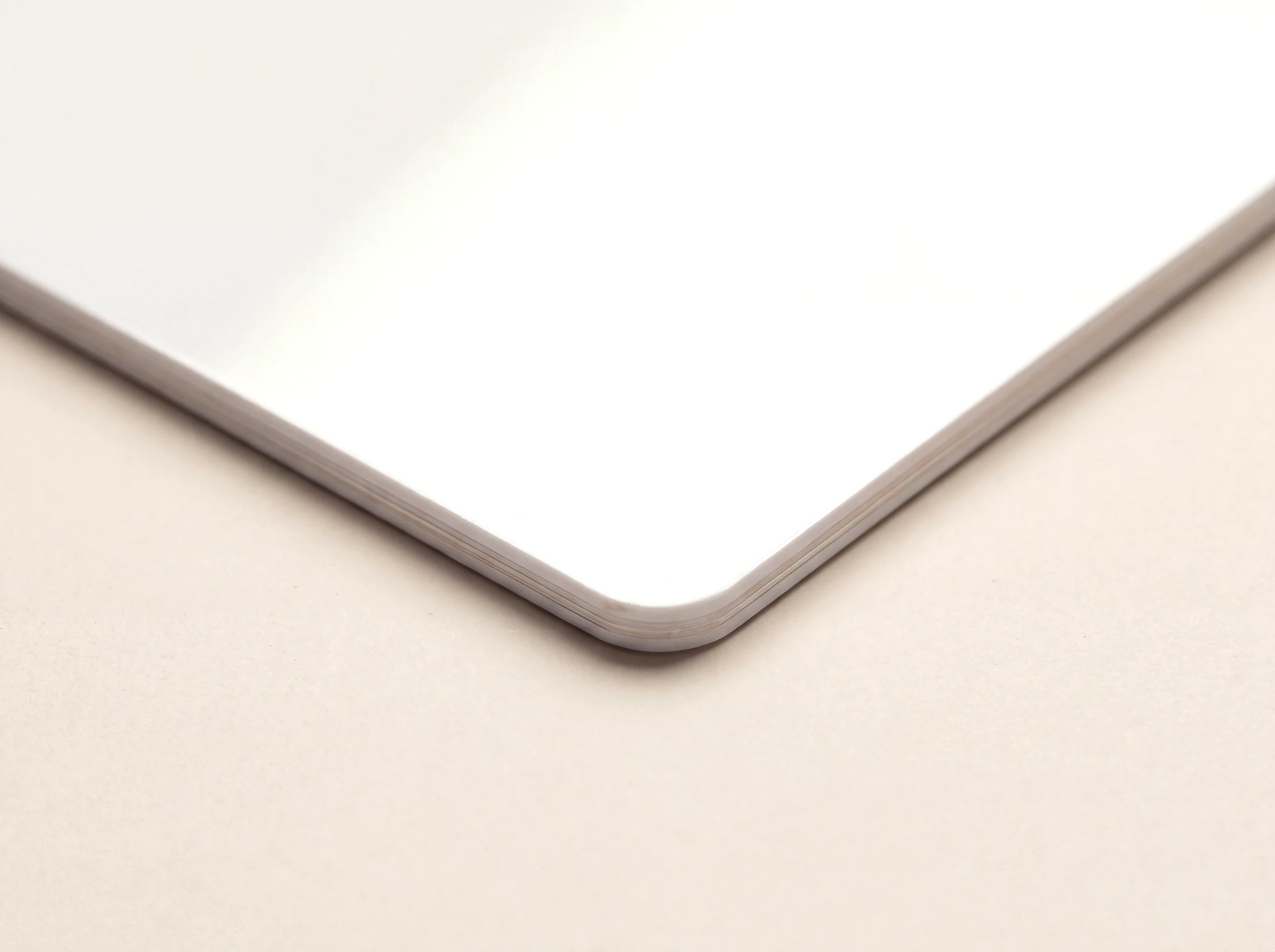 Close up of the corner of a gloss white PVC card, showing the laminated edge