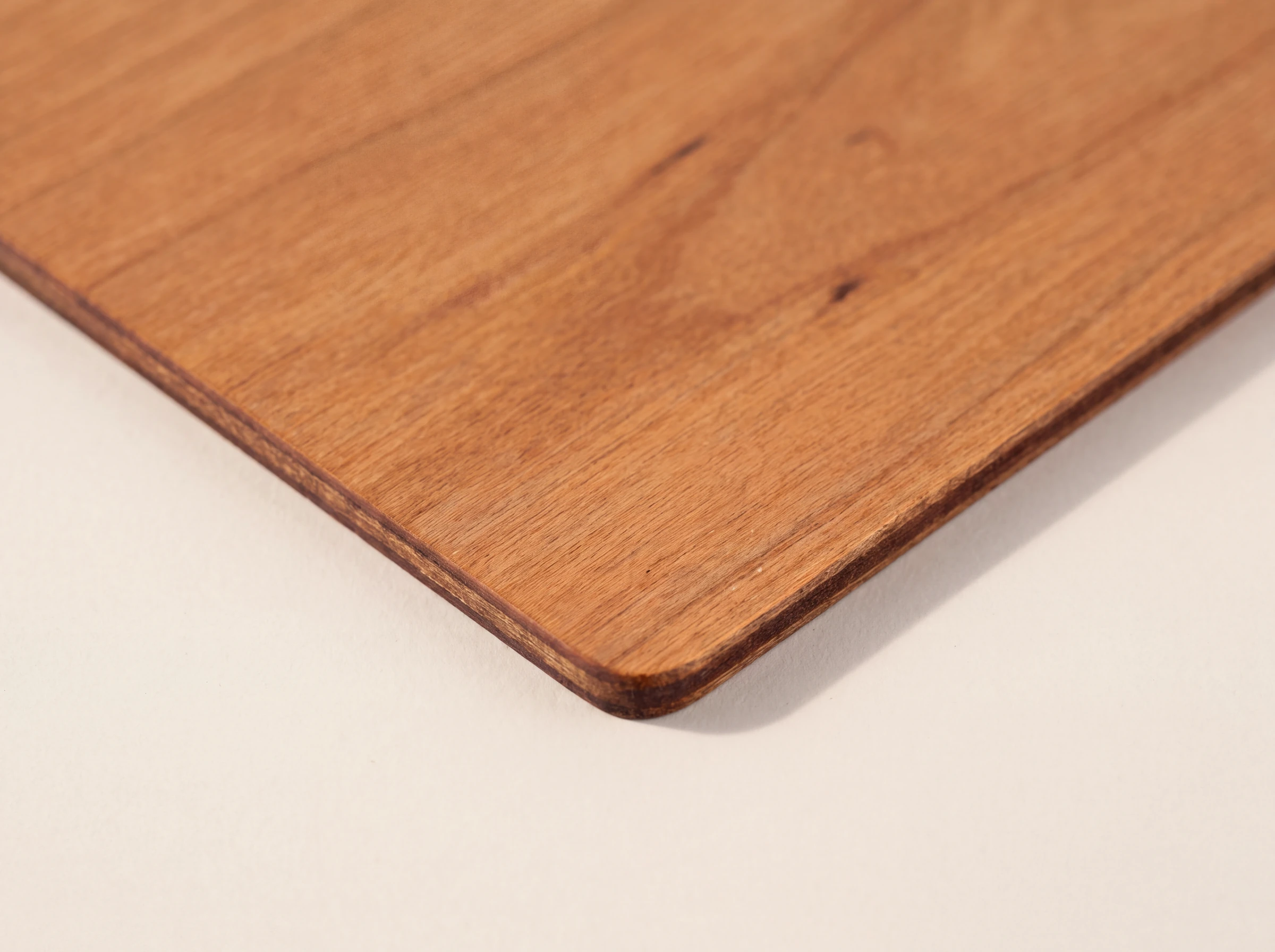 Close up of the corner of a cherry wood card, showing the grain and the laser cut edge
