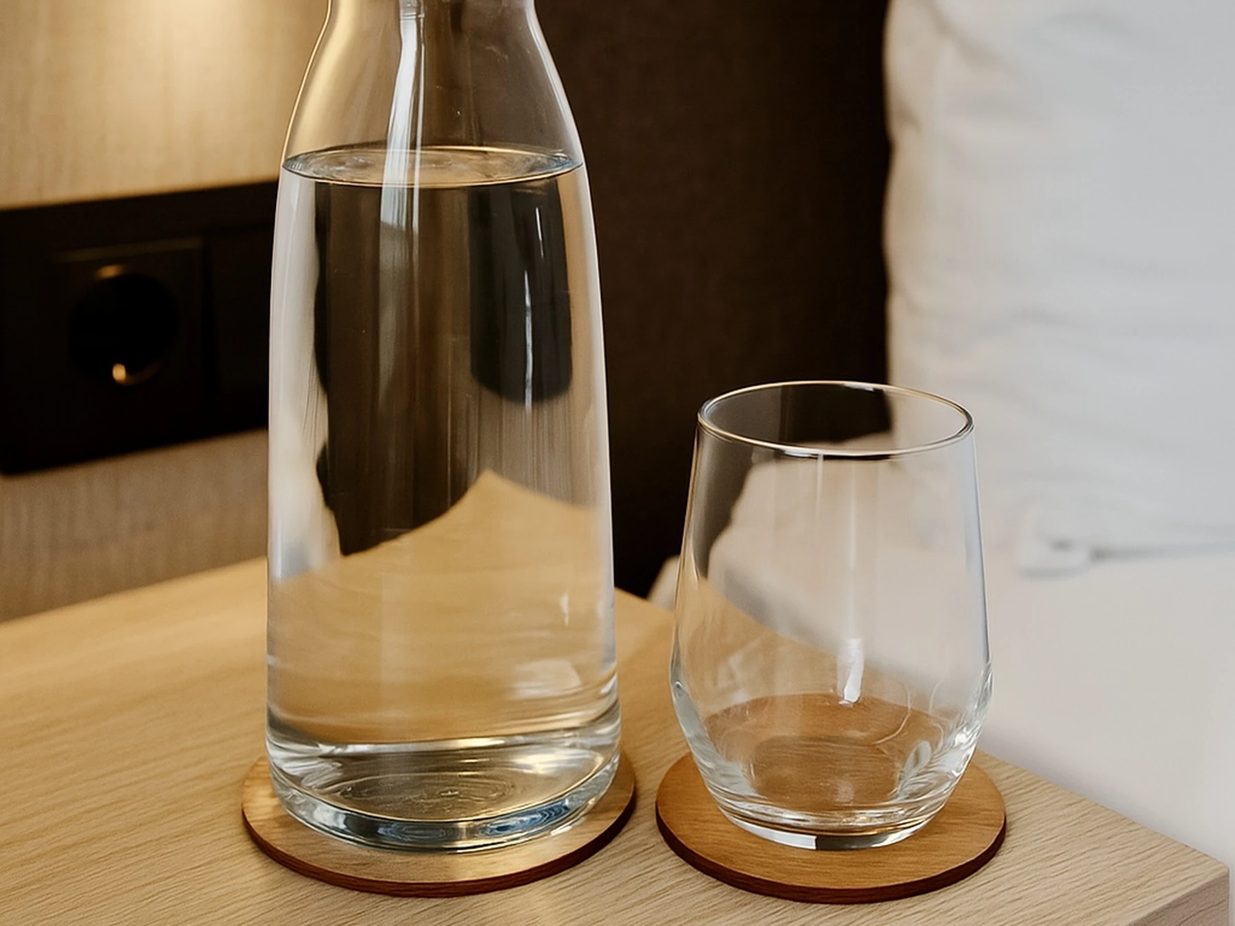 Wooden coasters under a carafe and glass on a bedside table