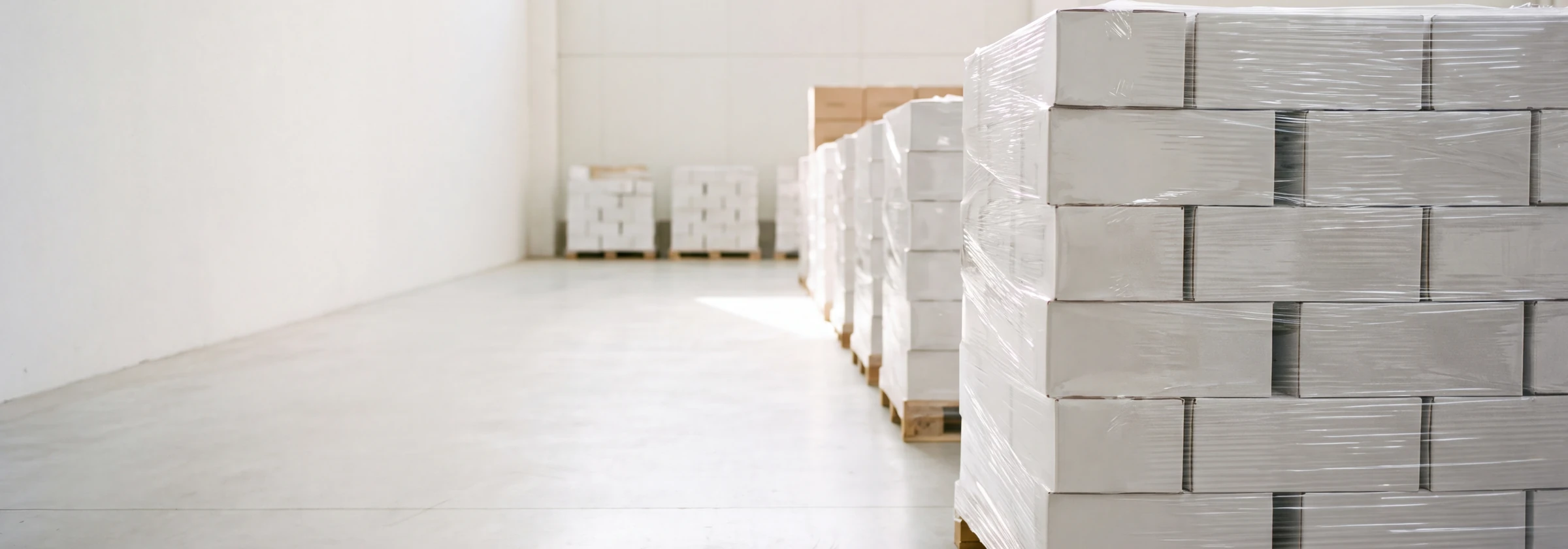 Pallets of shrink wrapped cartons of finished cards in a bright warehouse