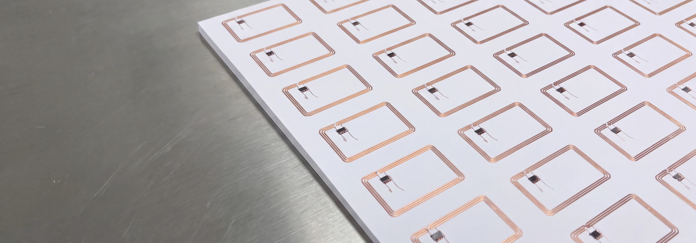 A sheet of RFID inlays with their copper antennas and chips, on the production bench