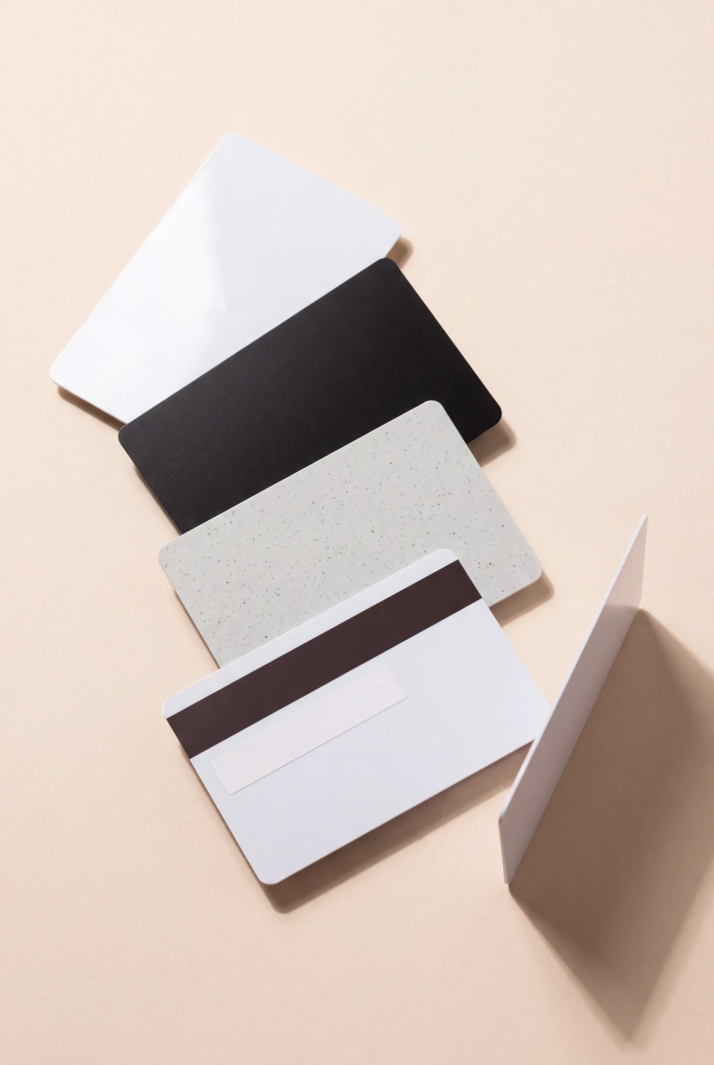 Blank PVC cards in white, matt black and recycled grey, one showing the magnetic stripe and signature panel