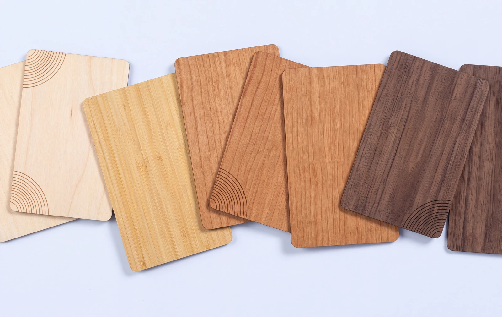 Wooden cards in basswood, bamboo, cherry and black walnut, overlapping flat, some with a laser engraved corner pattern