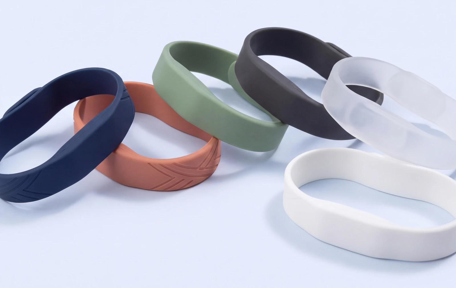 Blank silicone wristbands in navy, terracotta, sage, charcoal, frosted and plain white, one with a debossed pattern