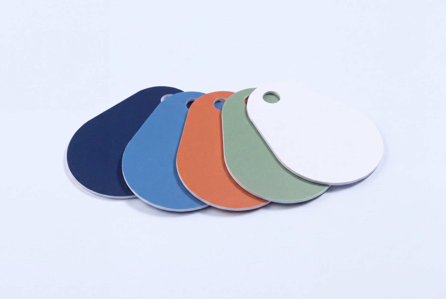 Five gloss laminated PVC key tags in a teardrop shape, fanned out in navy, blue, terracotta, sage and white, each with a punched hole
