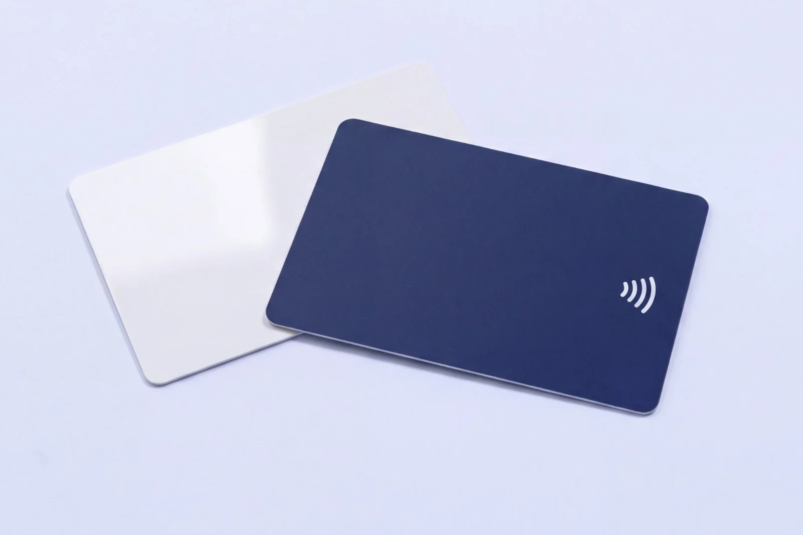 Two RFID cards, one gloss white and one matte navy printed with a contactless symbol