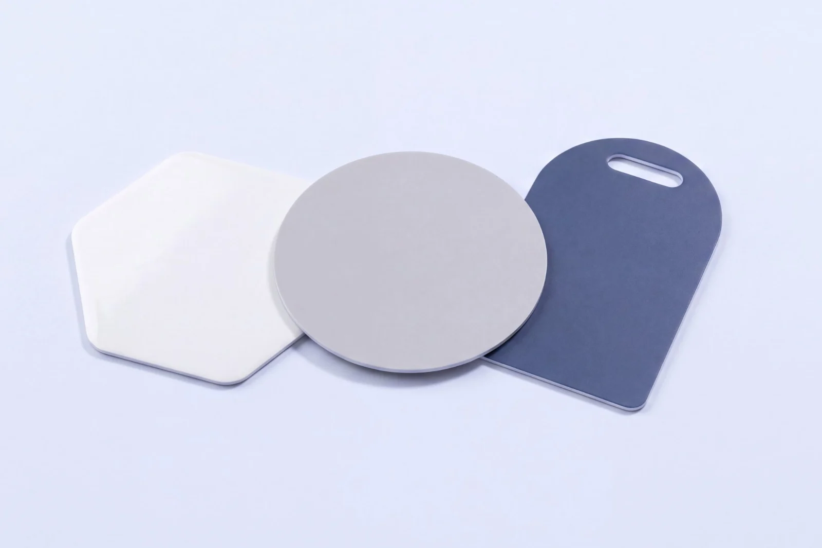 Three RFID cards cut to special shapes: a white hexagon, a grey circle and a navy key tag with a slot