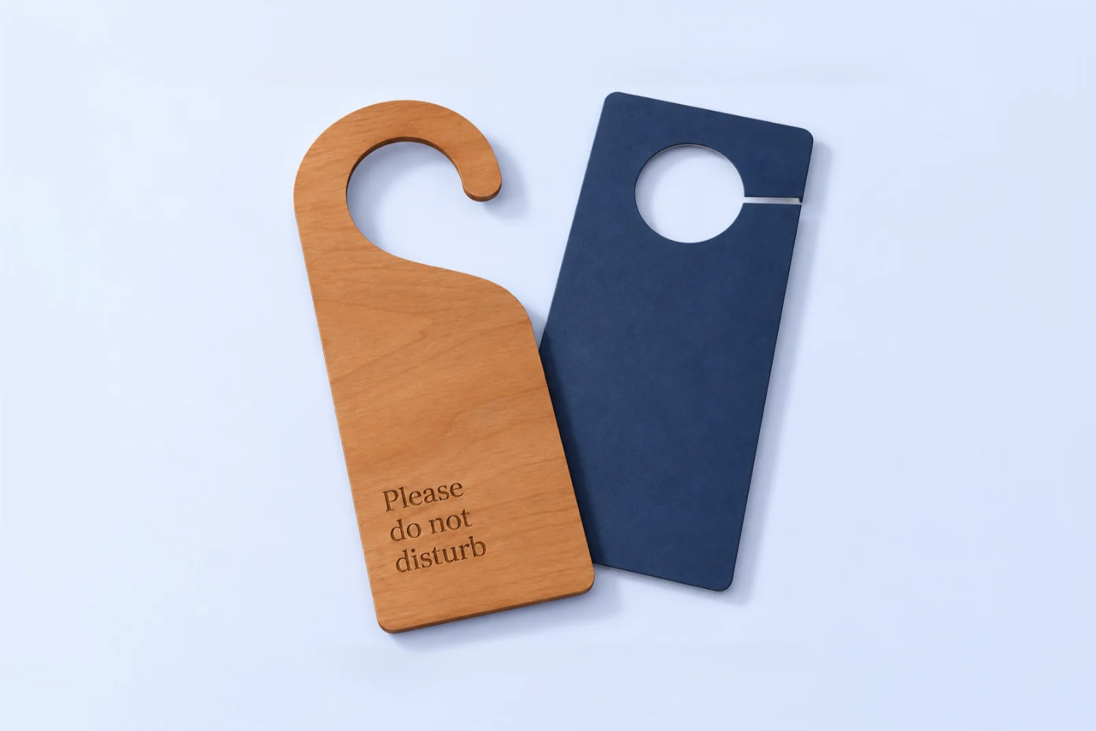Two hotel door hangers: cherry wood with a hook cut-out and engraved Please do not disturb, and a plain navy printed board with a round hole and slit
