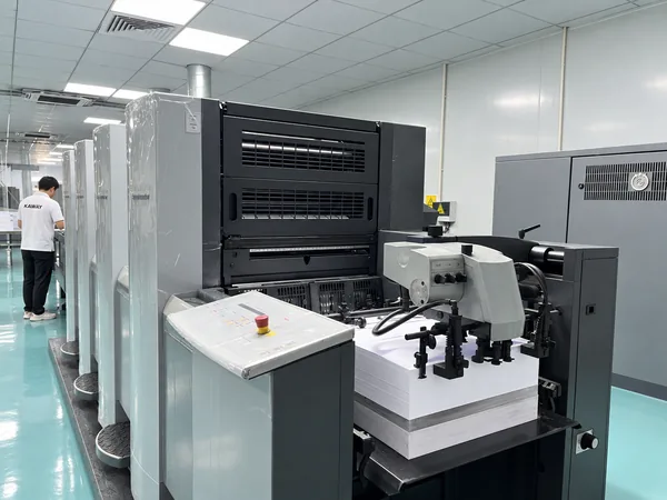 Four-colour offset press at the plant in Dongguan, with an operator at the far end