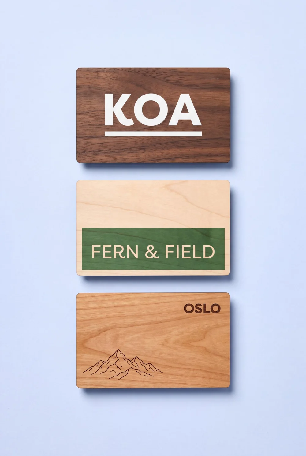 Three wooden RFID cards in walnut, birch and cherry, each printed with a different design