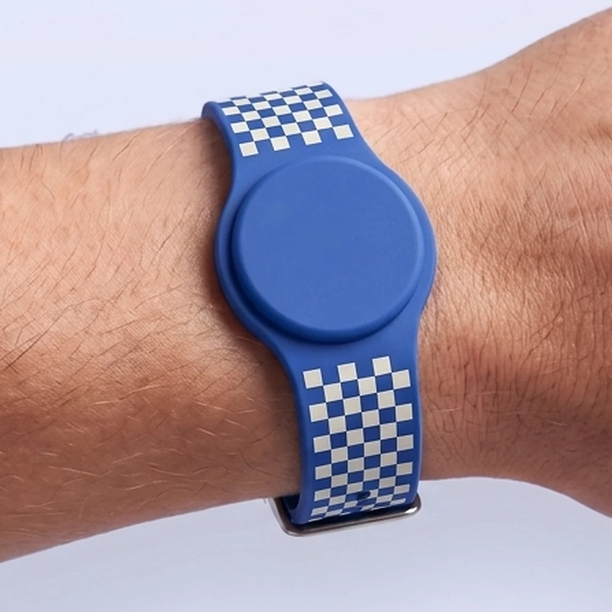 Cobalt blue silicone RFID watch wristband with a round chip housing and an ivory checkerboard print on the strap, worn on a wrist