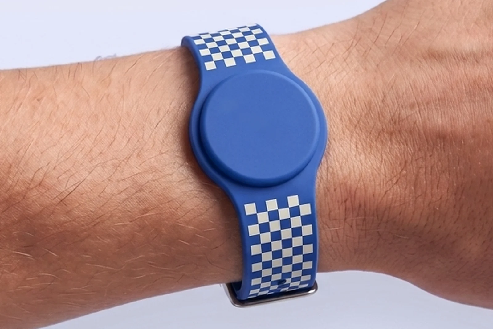 Cobalt blue silicone RFID watch wristband with a plain round chip housing and an ivory checkerboard print on the strap, worn on a wrist