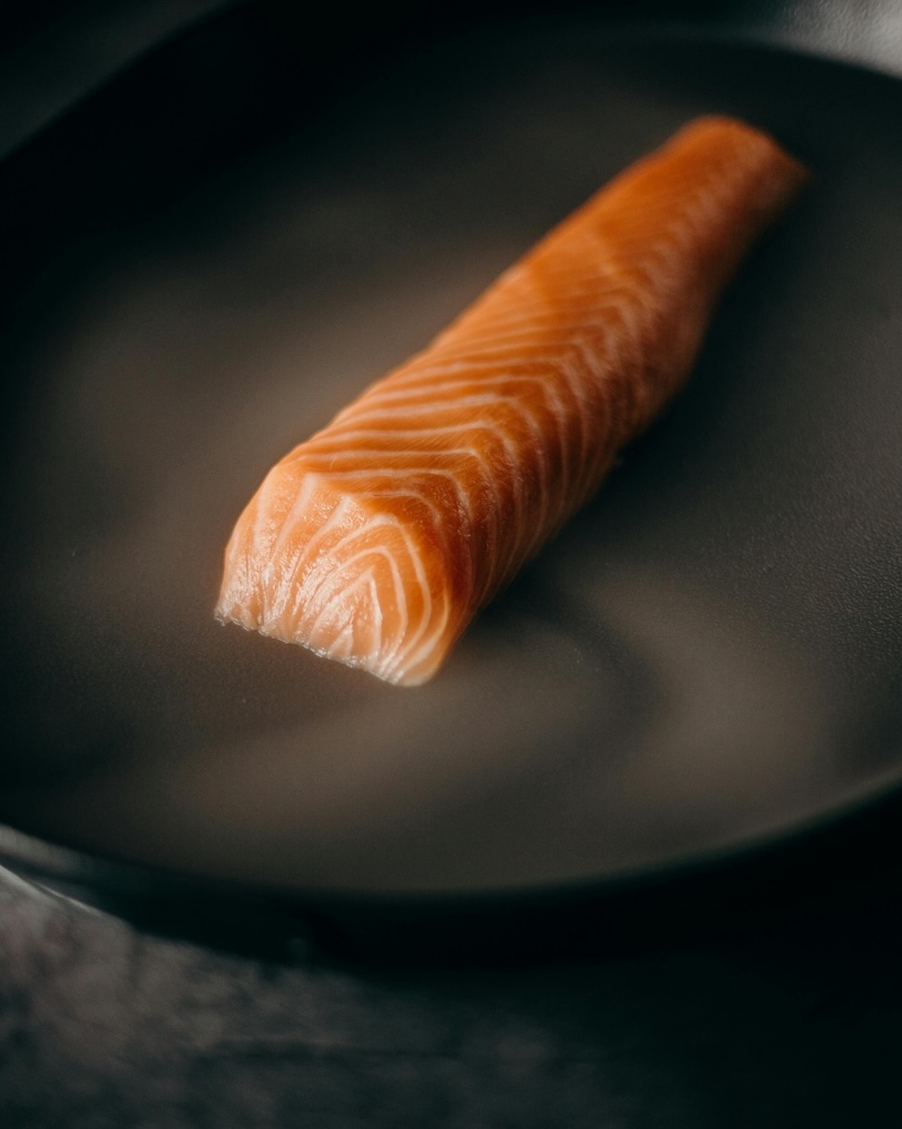 Raw salmon fillet placed in a black frying pan.