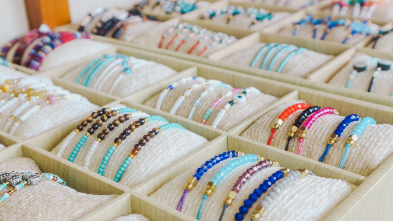 Display of colorful beaded bracelets organized in a wooden tray with multiple compartments.