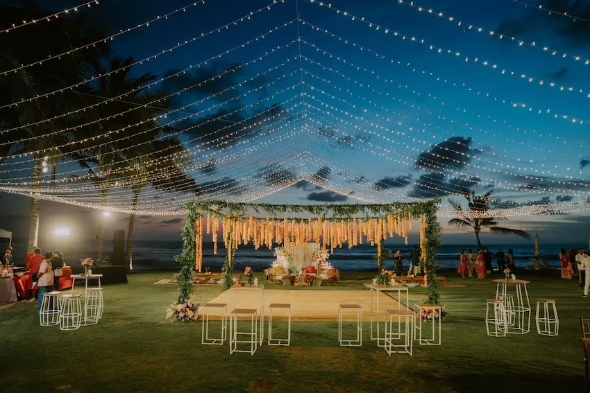 Evening celebration under hanging lights and a floral canopy on the lawn