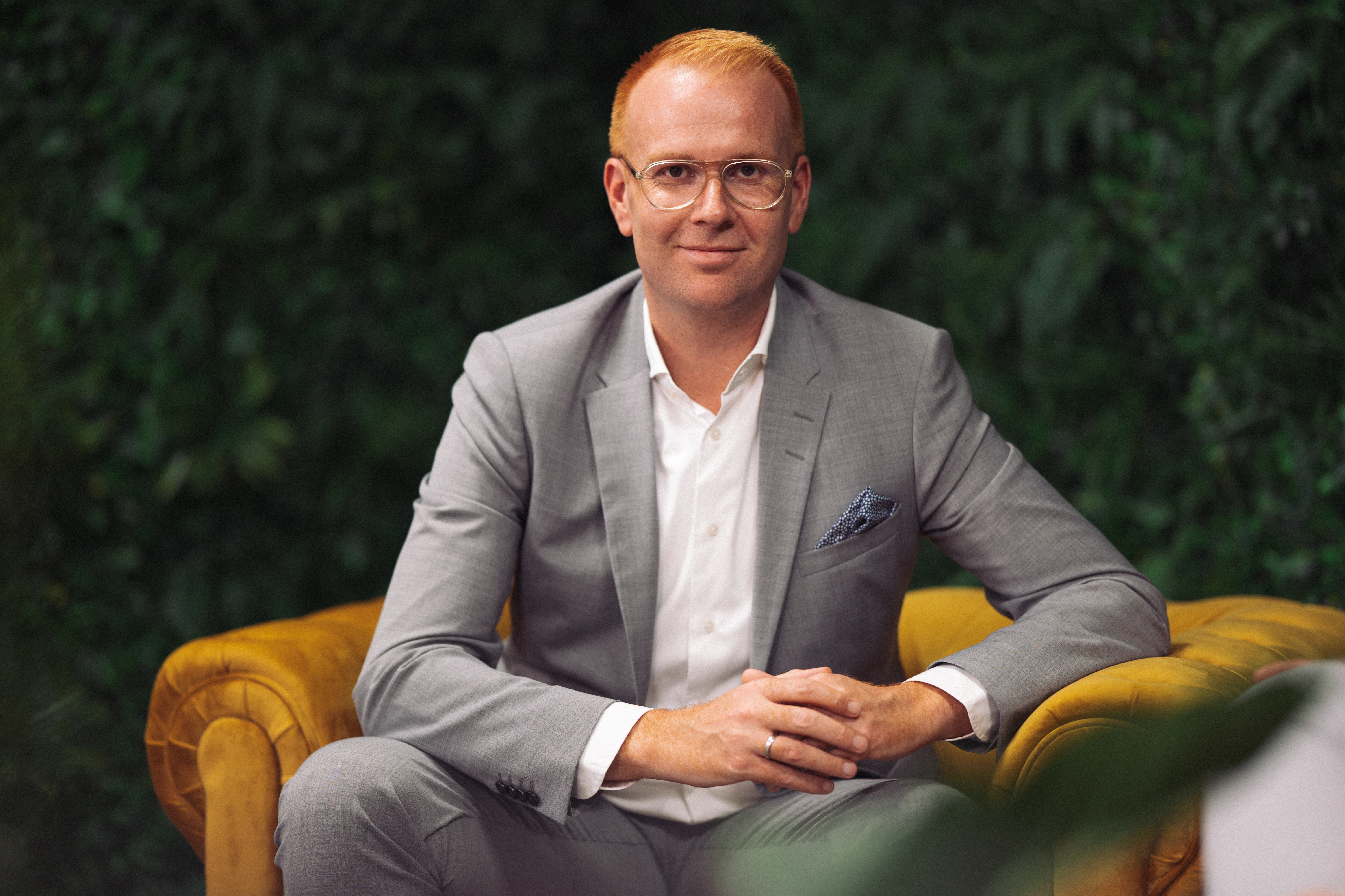 Zwei Männer mit verschränkten Armen stehen vor einer Wand, die mit US-Dollar-Scheinen bedeckt ist.