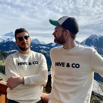 Deux membres de l’équipe Hive en sweatshirts de marque devant un panorama alpin