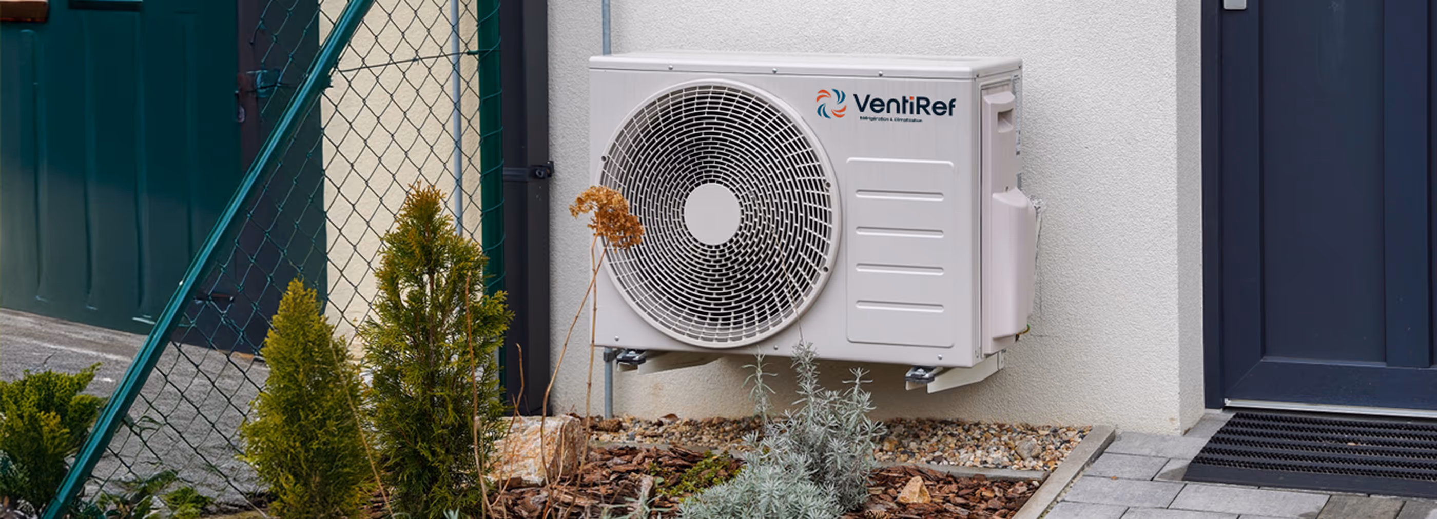 Unité de climatisation VentiRef blanc sur façade, avec arbustes verts