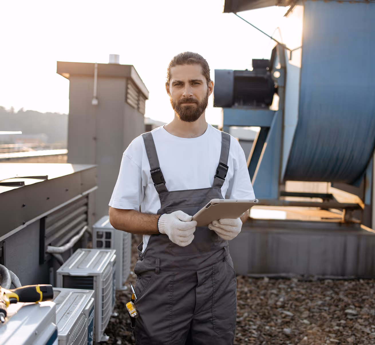 Ouvrier sur un toit tenant une tablette électronique, équipement industriel visible